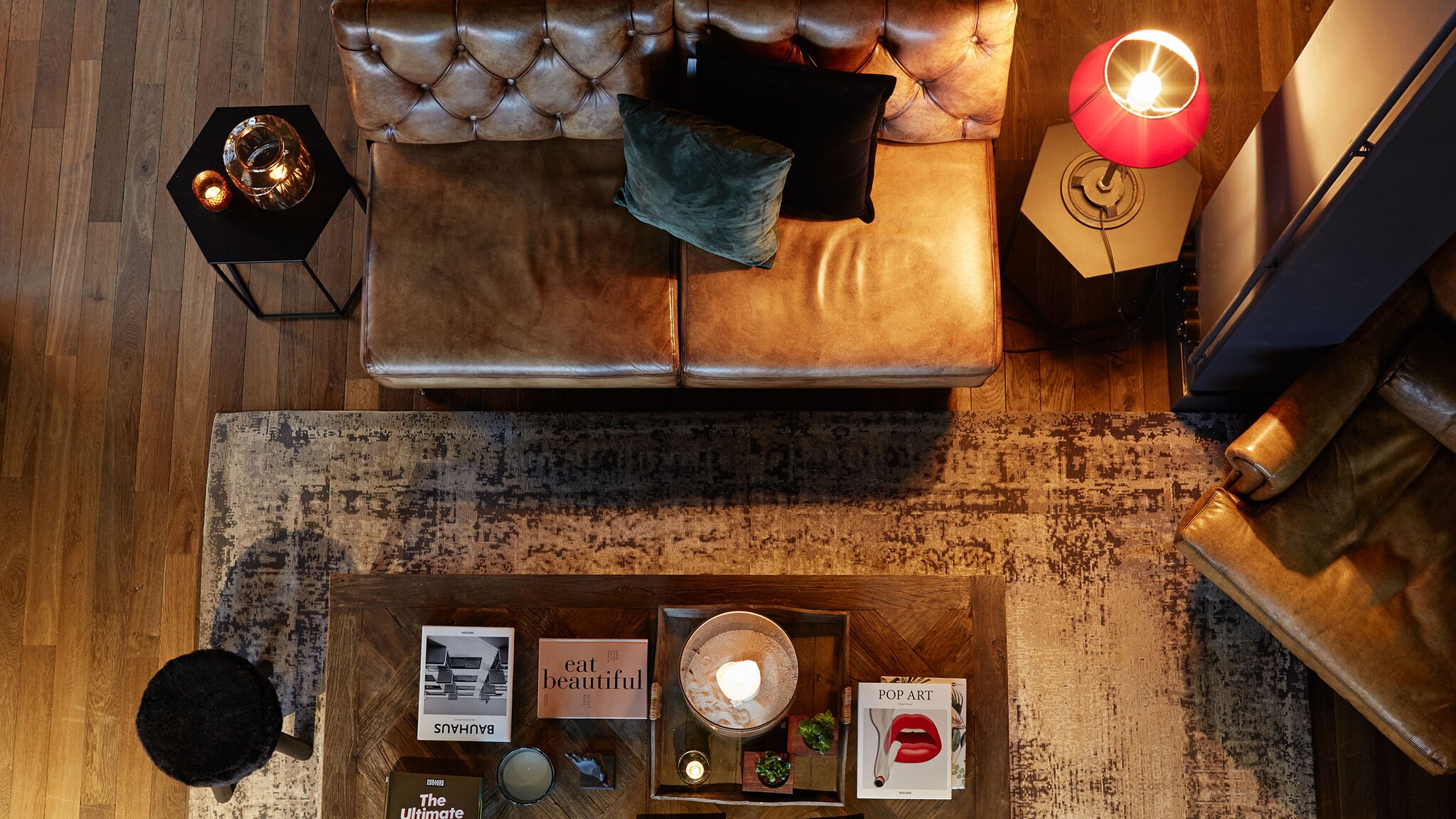 Vogelperspektive eines Sofas, das vor einem Tisch steht mit stilvollen Lampen und Accessoires.
