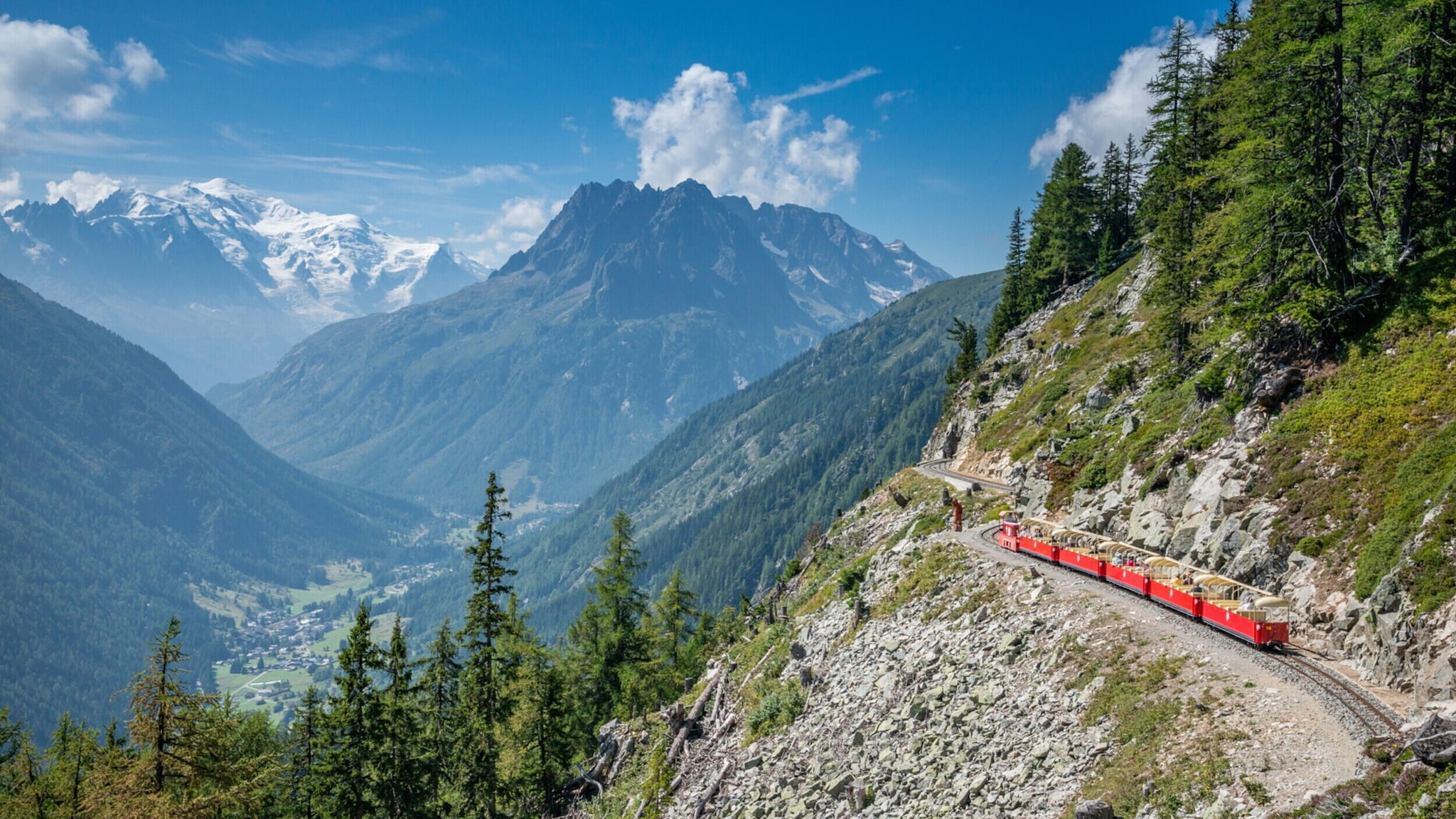 Bahn Emosson Ein Panoramazug fährt am Bergrand entlang, im Hintergrund ist der Mont Blanc zu sehen.