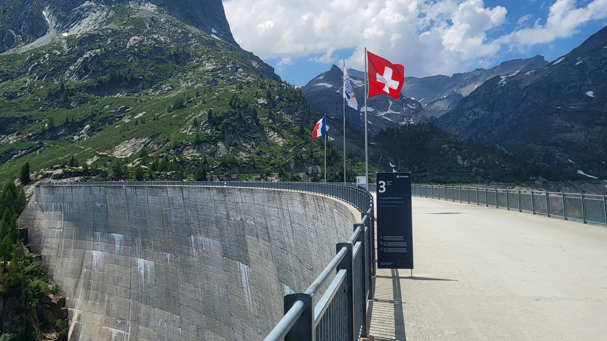Blick auf die Überquerung auf dem Emosson Staudamm mit der schweizerischen und französischen Flagge. 