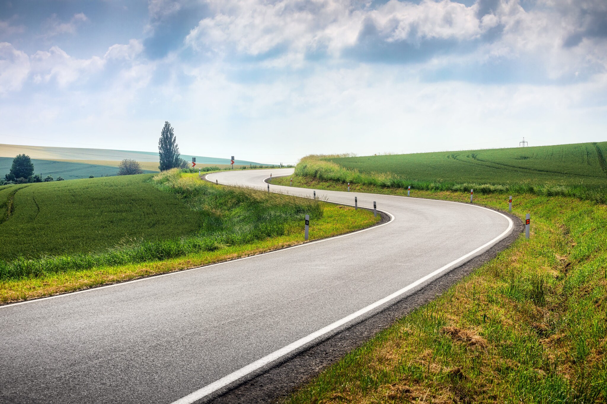 Kurvige Straße durch grüne Felder in Tschechien.