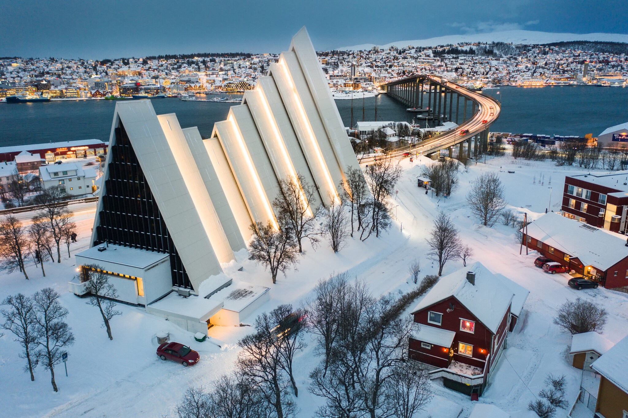 Beleuchtete und verschneite Brücke, Kathedrale und Häuser von Tromsø.