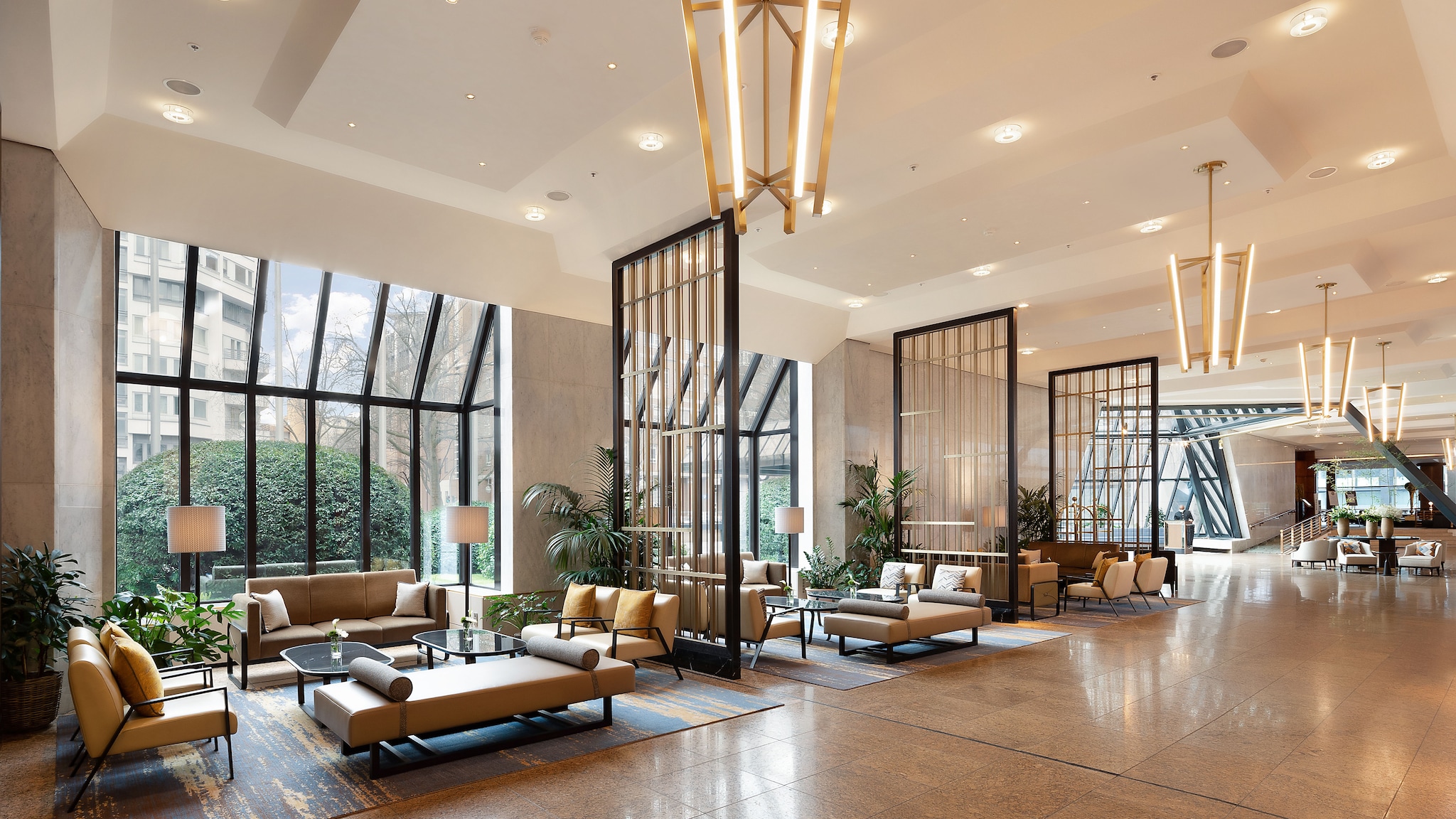 In einer großen Hotellobby stehen verschiedene Loungemöbel, an der Decke hängen abstrakte Kronleuchter.