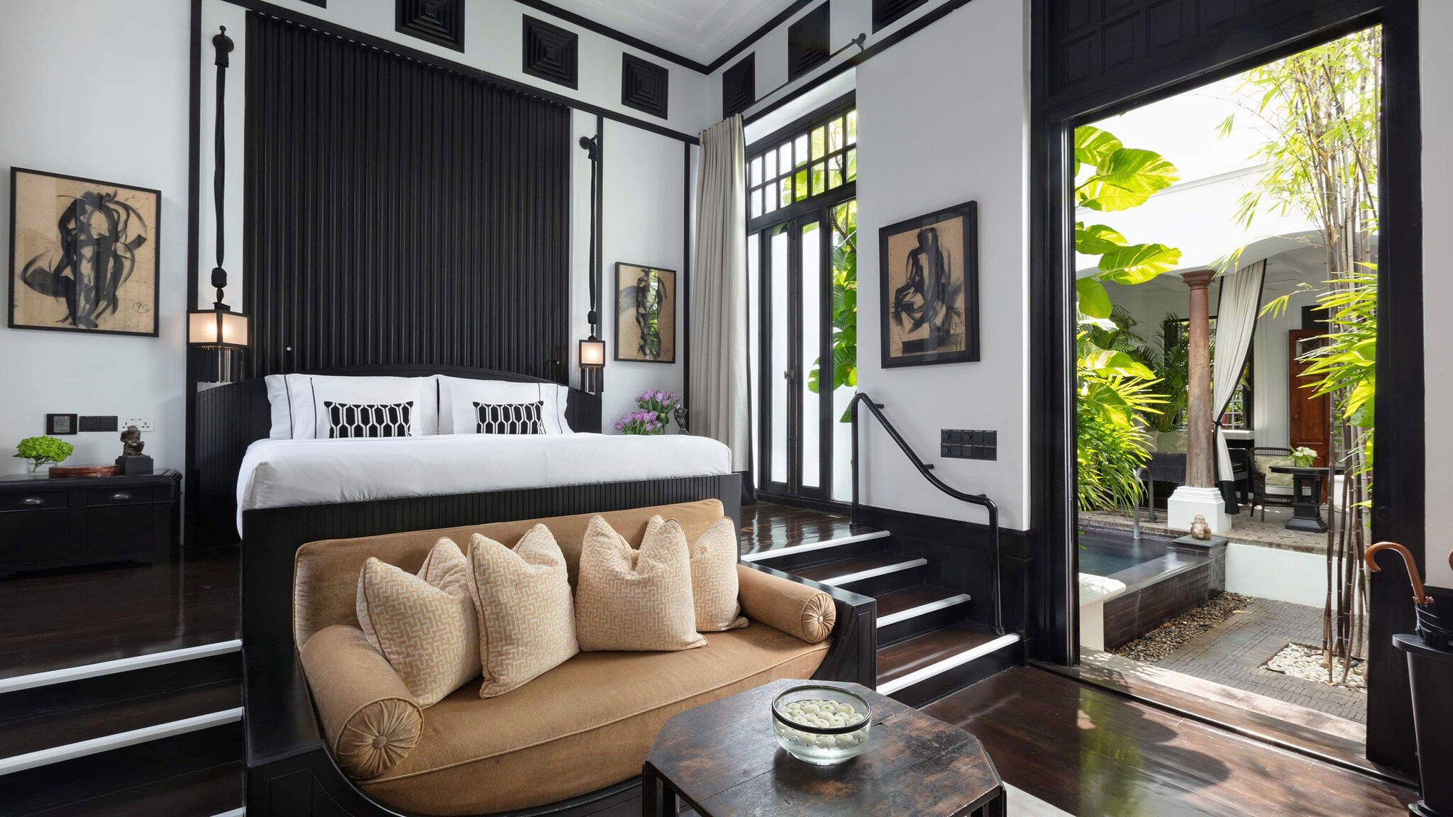 In einer Hotelsuite steht ein Bett und ein Sofa vor einer Terrasse.