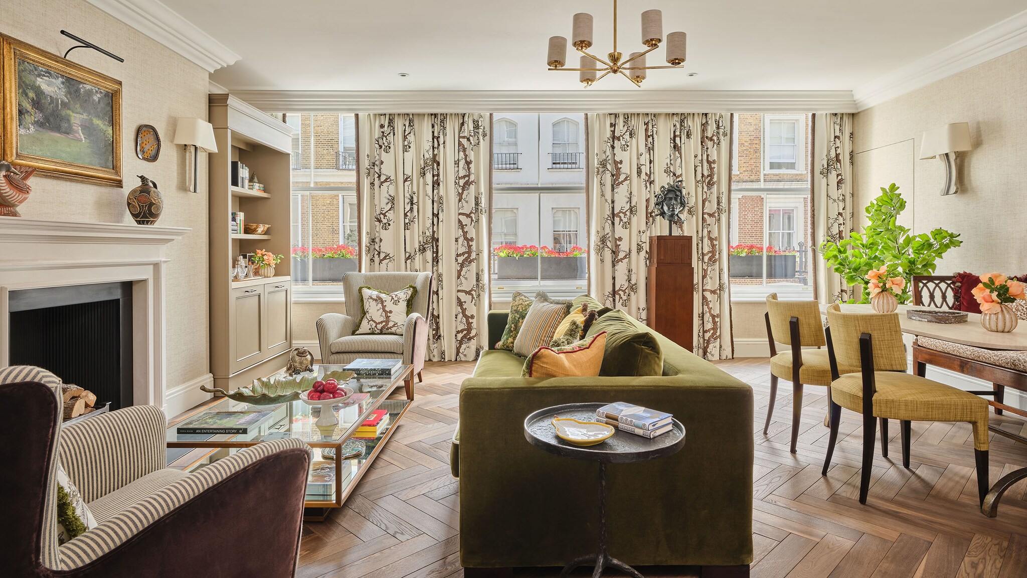 In einer Hotelsuite steht ein grünes Sofa und andere Loungemöbel vor einem Fenster mit bunten Vorhängen.
