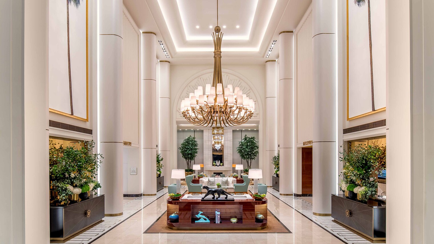 In der großen Empfangshalle eines Hotels, mit hohen weißen Wänden, stehen Loungemöbel und Kunstwerke.