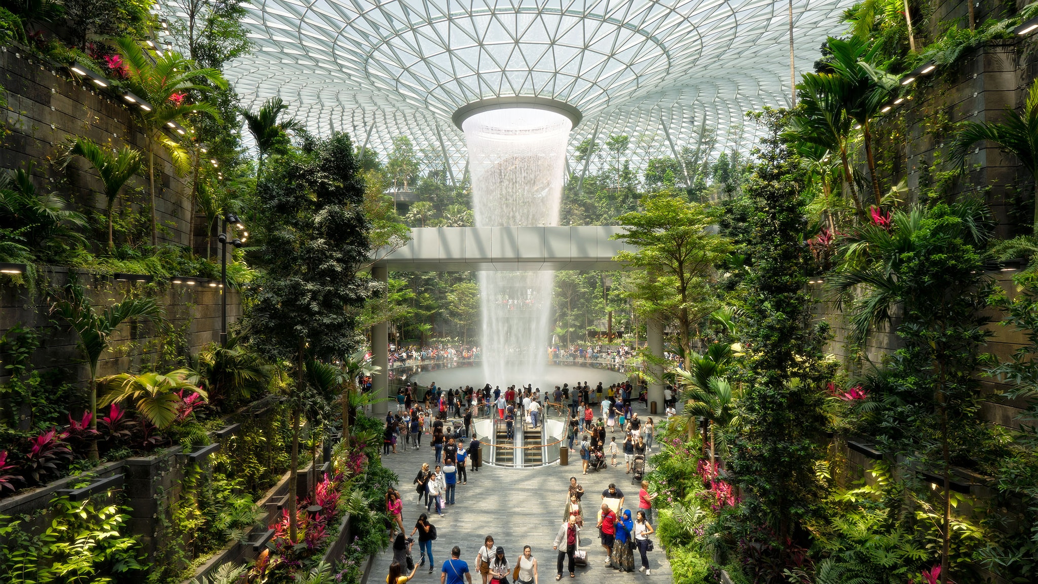 Schönste Flughäfen – Singapur Menschen in einem Flughafenterminal mit vertikalen Gärten und Wasserfall unter einer Glaskuppel. hängenden Gärten und