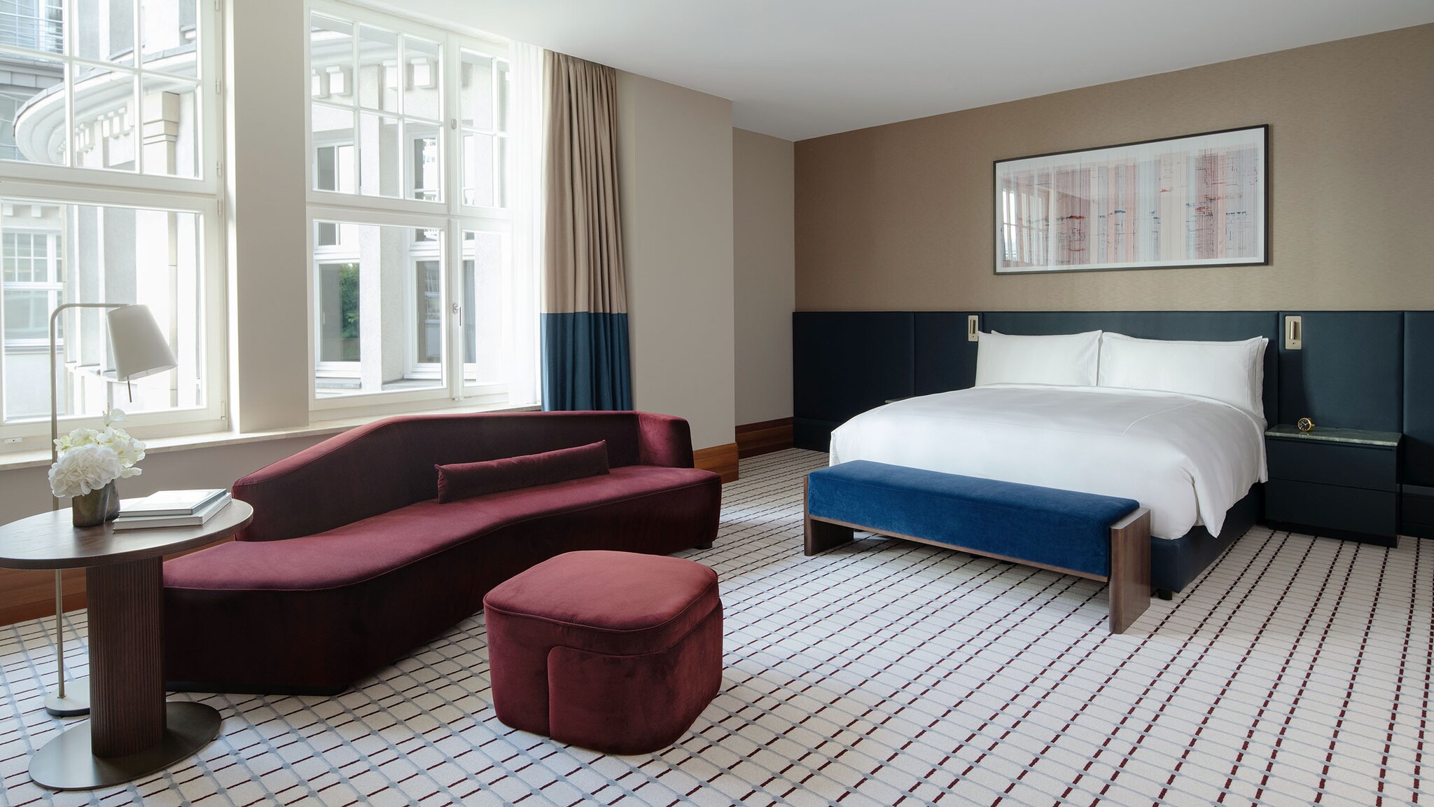 In der Juniorsuite eines Hotels steht ein großes Bett und ein Sofa mit Tisch.