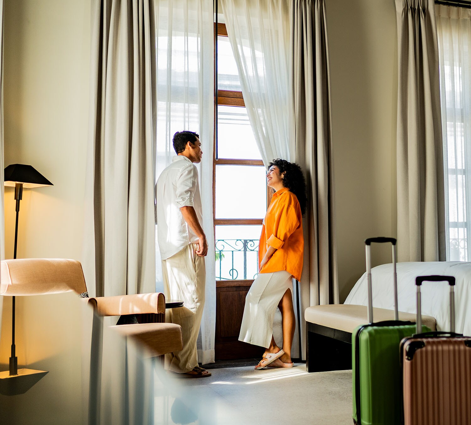 Ein Mann und eine Frau stehen entspannt an einem Fenster in einem hellen, modernen Hotelzimmer.