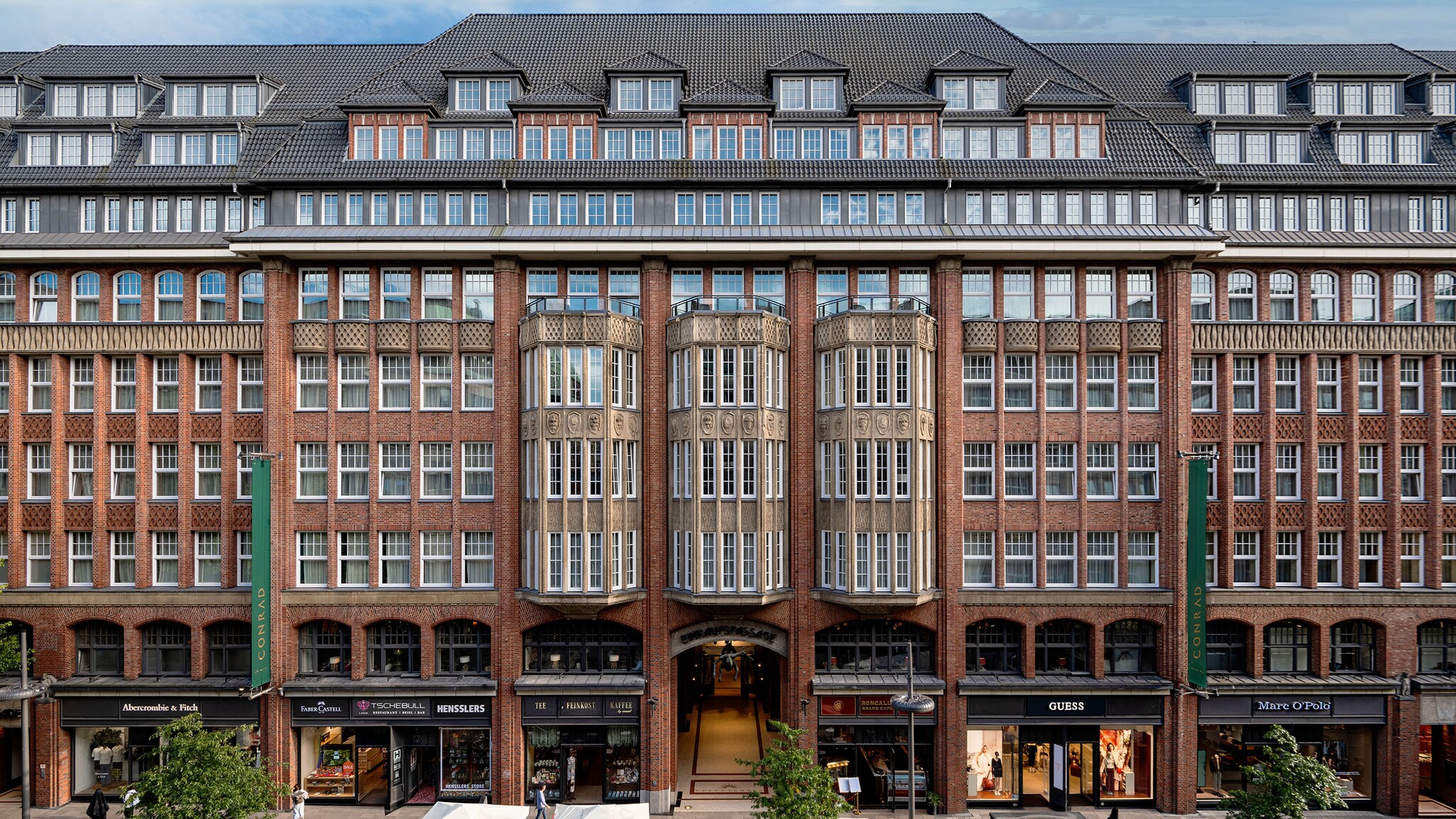 Ein historisches Gebäude mit verzierten Fenstern und kleinen Läden befindet sich an einer Einkaufsstraße.