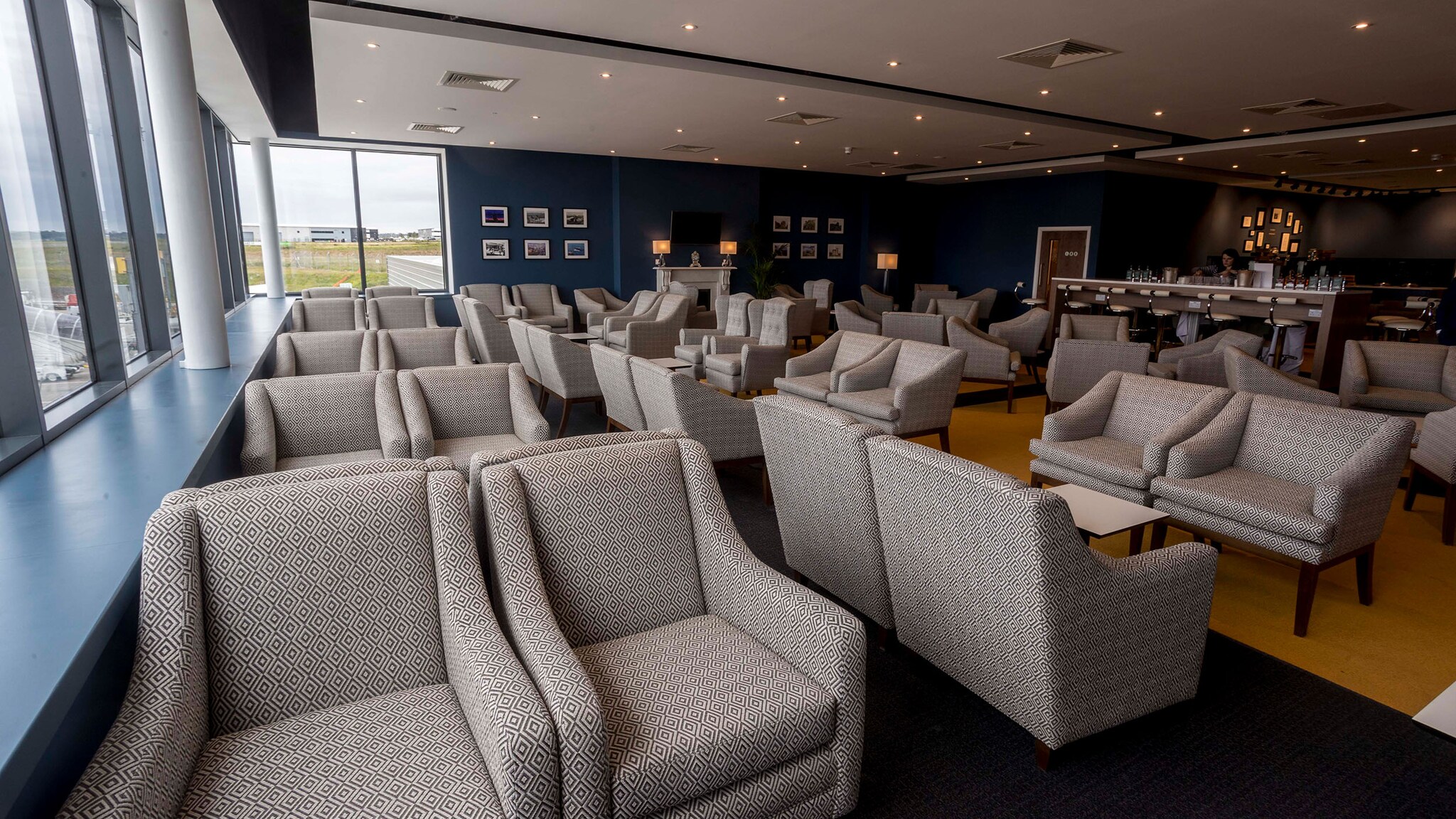 Flughafenlounge mit grauen Sesseln und Blick aufs Rollfeld.
