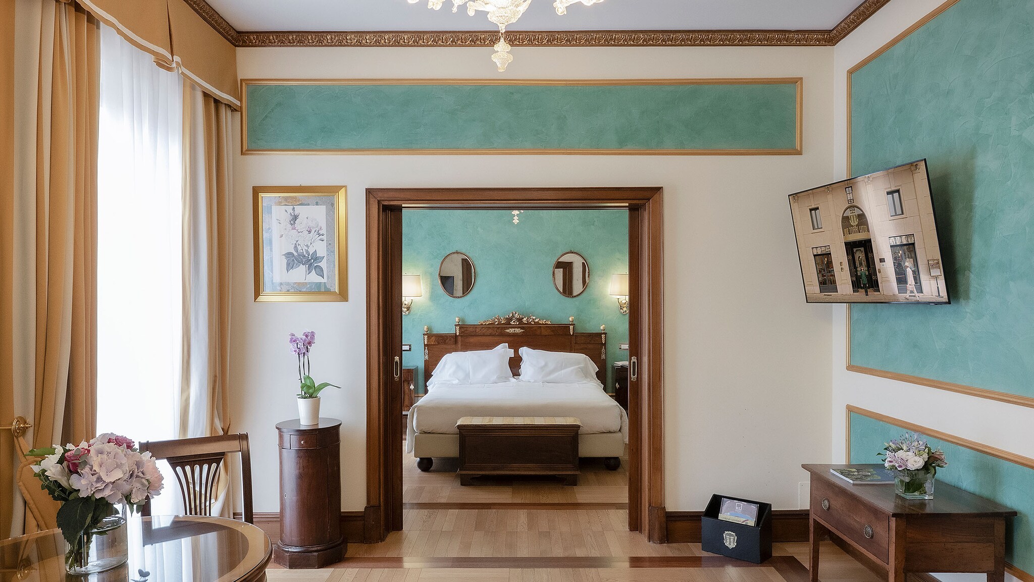 In einem großzügigen Hotelzimmer mit Durchgang steht ein Bett und weitere Möbel.