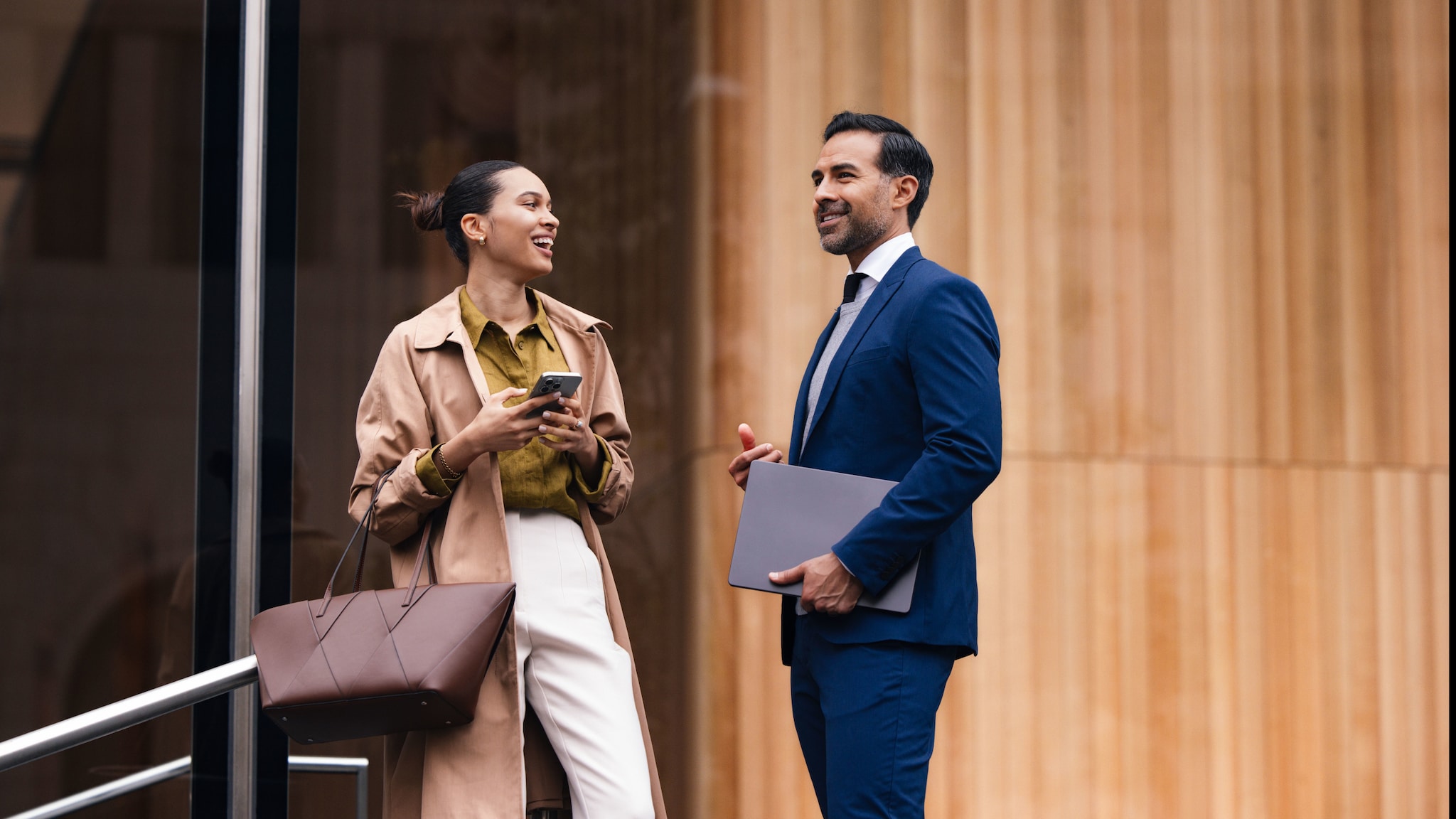Eine Frau und ein Mann stehen vor einem Gebäude und unterhalten sich, rechts im Bild ist die Business Gold Card von American Express eingeblendet.