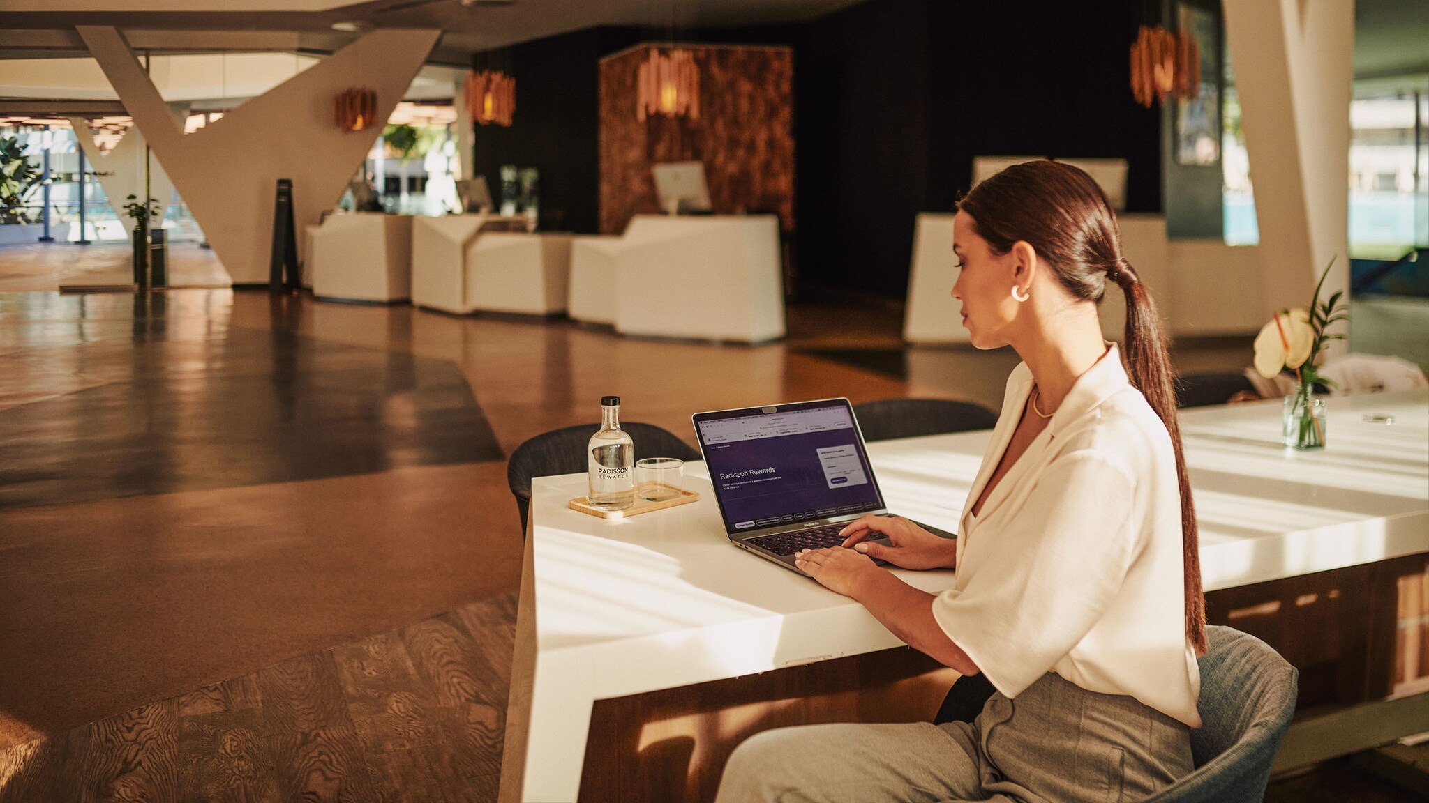 Eine Frau sitzt in einer Hotel-Lobby und schaut auf ein Tablet.