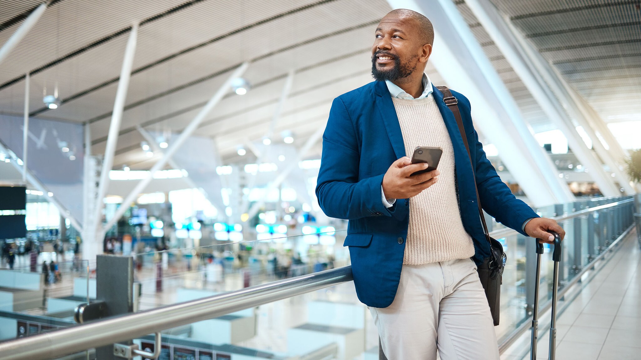 Ein Mann steht mit seinem Rollkoffer in einem Flughafen.