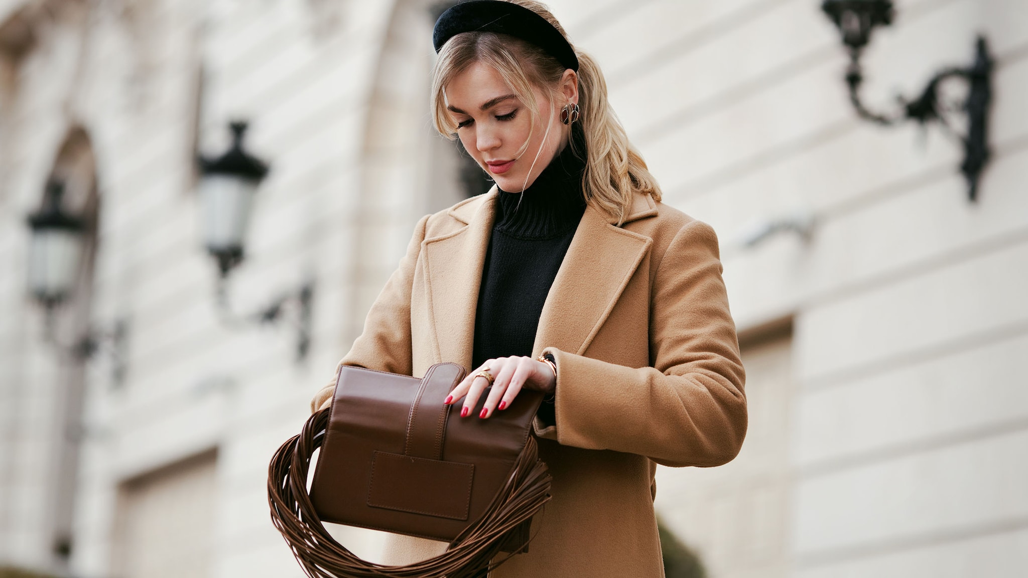 Eine Frau steht auf der Straße und schaut in ihre Handtasche.
