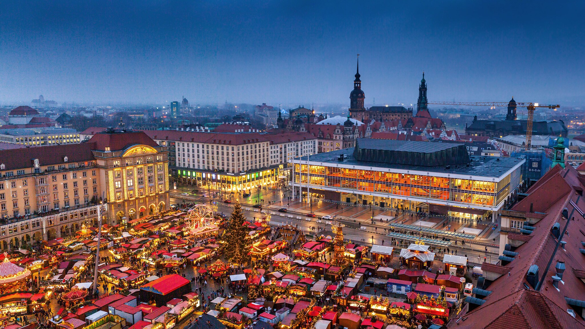Luftaufnahme von Dresdner Altstadtpanorama mit Weihnachtsmarkt bei Abenddämmerung.