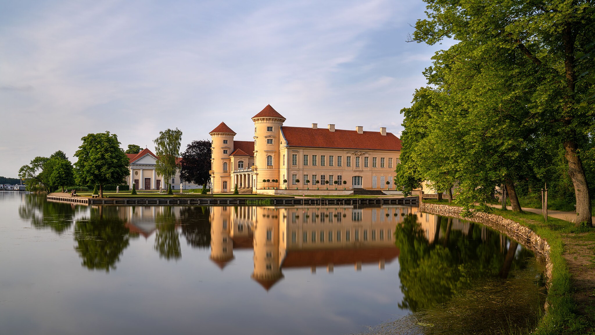 Ein Schloss am Ufer eines Sees spiegelt sich im Wasser.