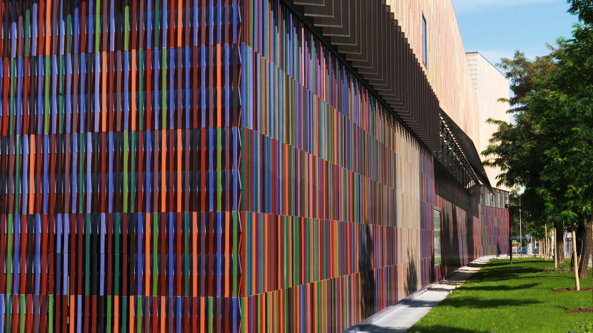 Außenansicht eines Museumsgebäude mit einer Fassade aus bunten Keramikstäbchen.