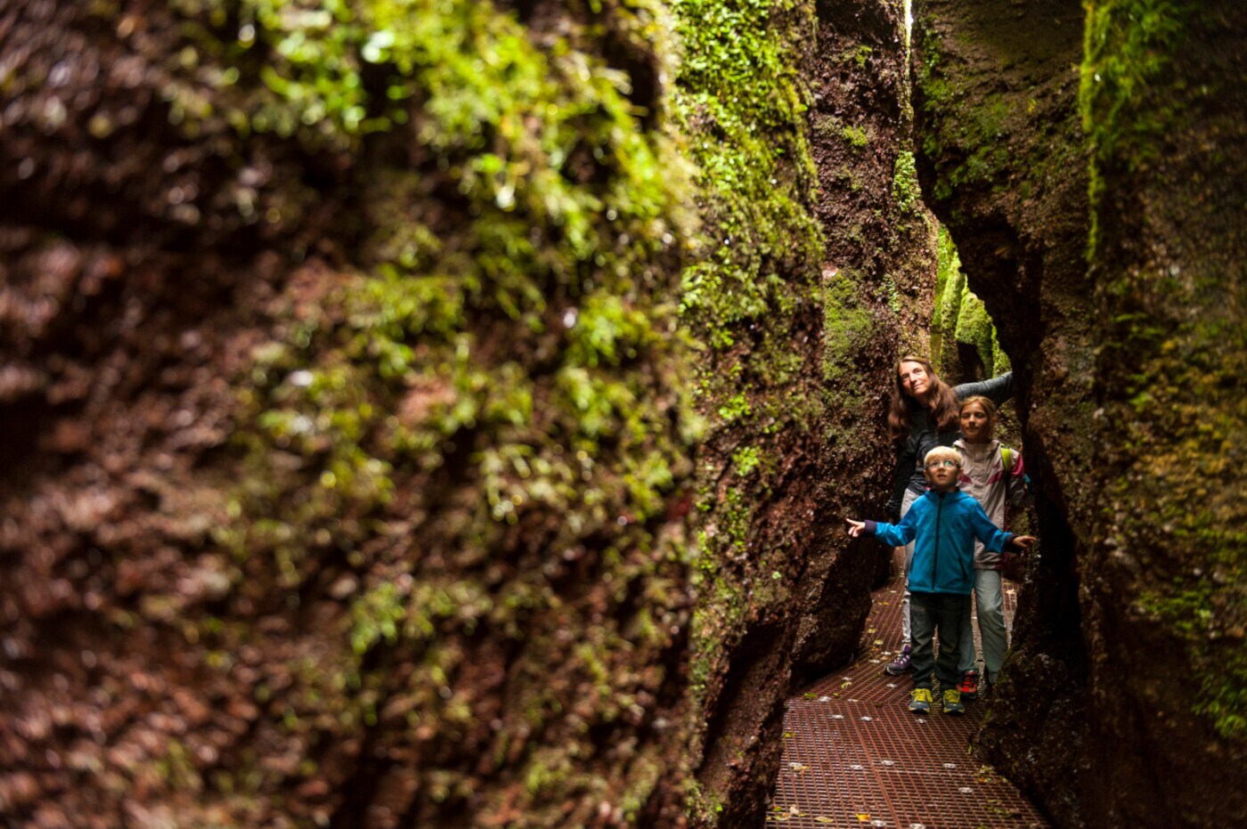 Eine Familie auf einem schmalen Weg an dem Felswände an beiden Seiten in die Höhe ragen Eine Familie auf einem schmalen Weg an dem Felswände an beiden Seiten in die Höhe ragen