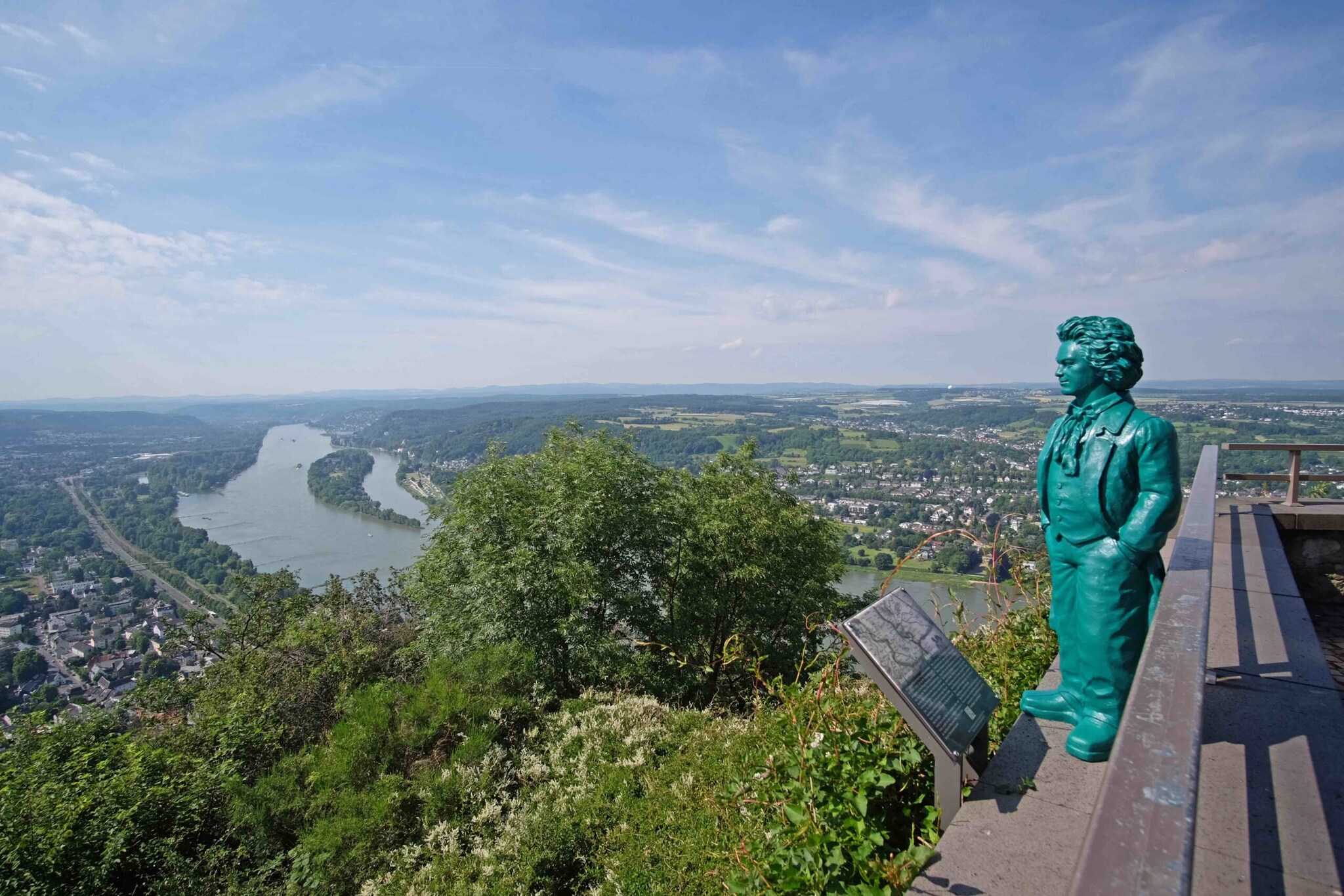 Blick von einem Aussichtsplateau auf das Rheintal mit einer kleinen Beethoven-Statue und grünen Pflanzen im Vordergrund