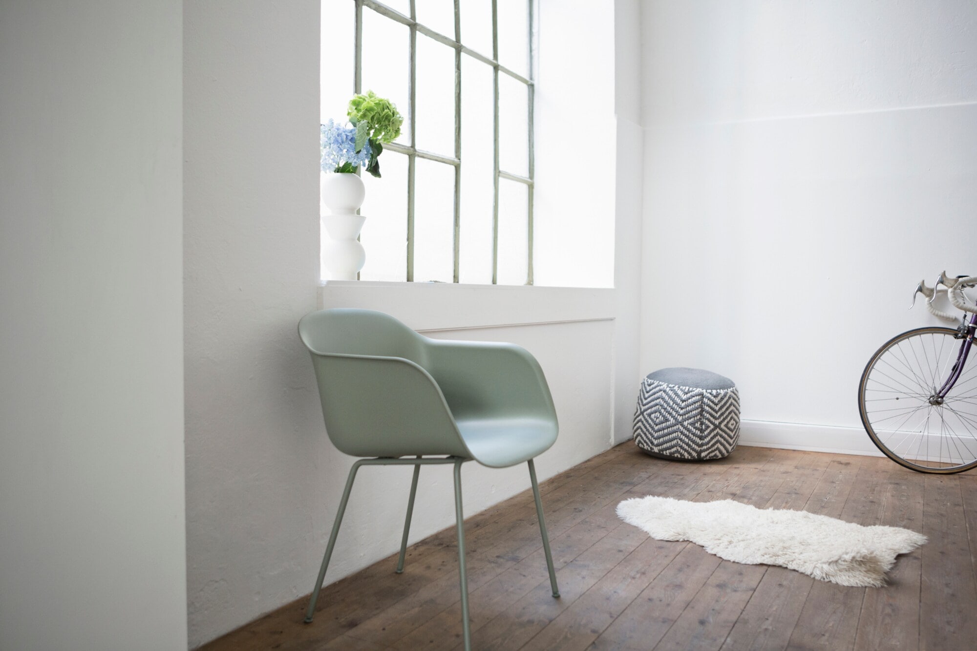 Ein grüner Stuhl aus Plastik steht an einer Wand neben einem Fenster Ein grüner Stuhl aus Plastik steht an einer Wand neben einem Fenster