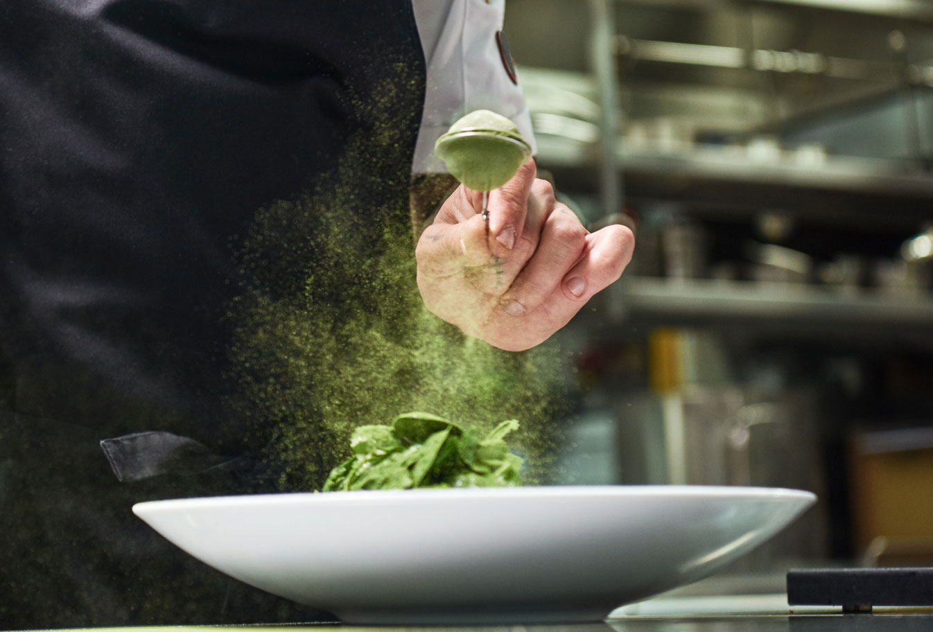 Koch würzt Gericht mit Matcha in Restaurantküche