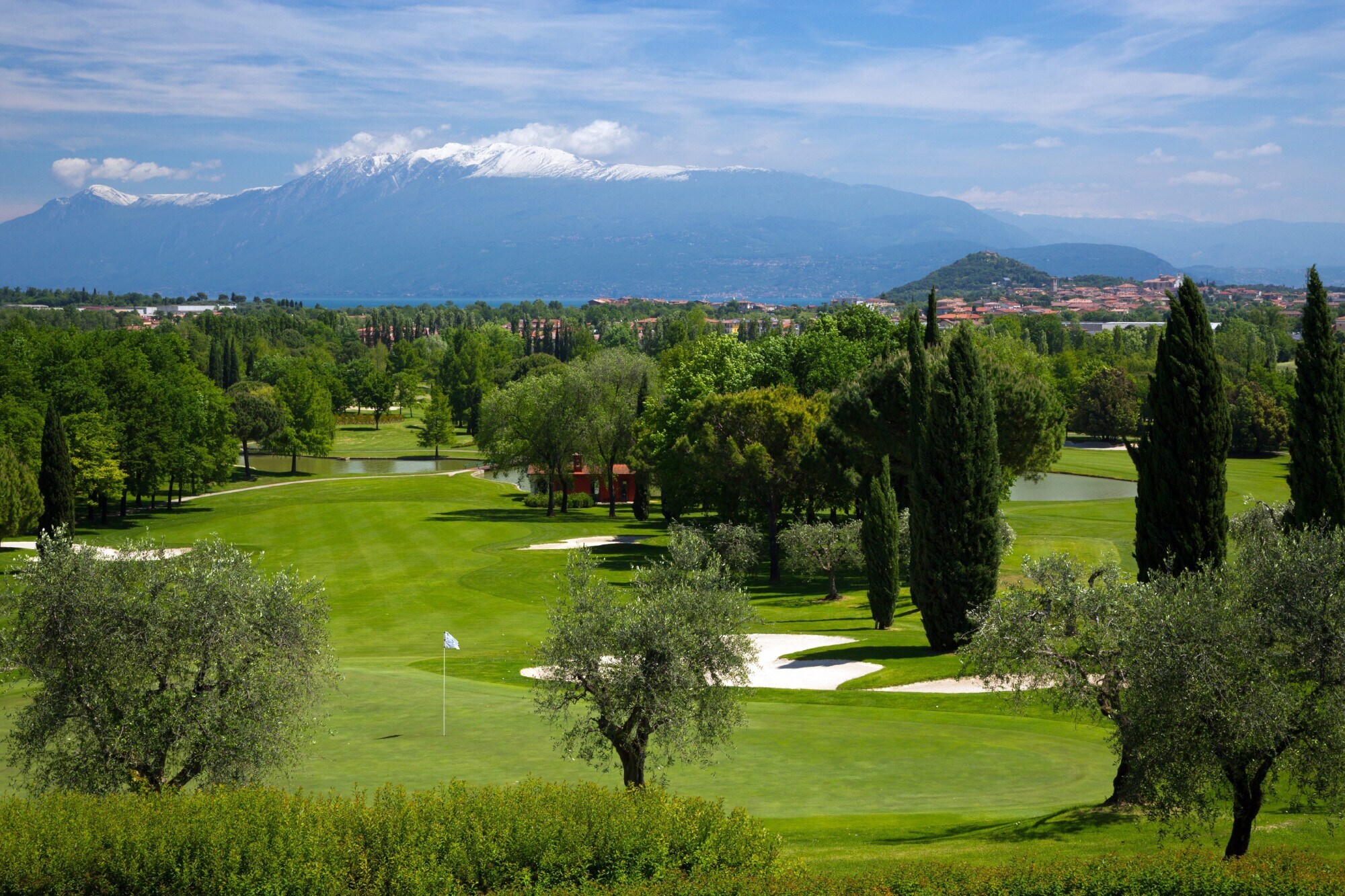 Ein Golfplatz umrandet von Bäumen mit Blick auf einen schneebedeckten Berg