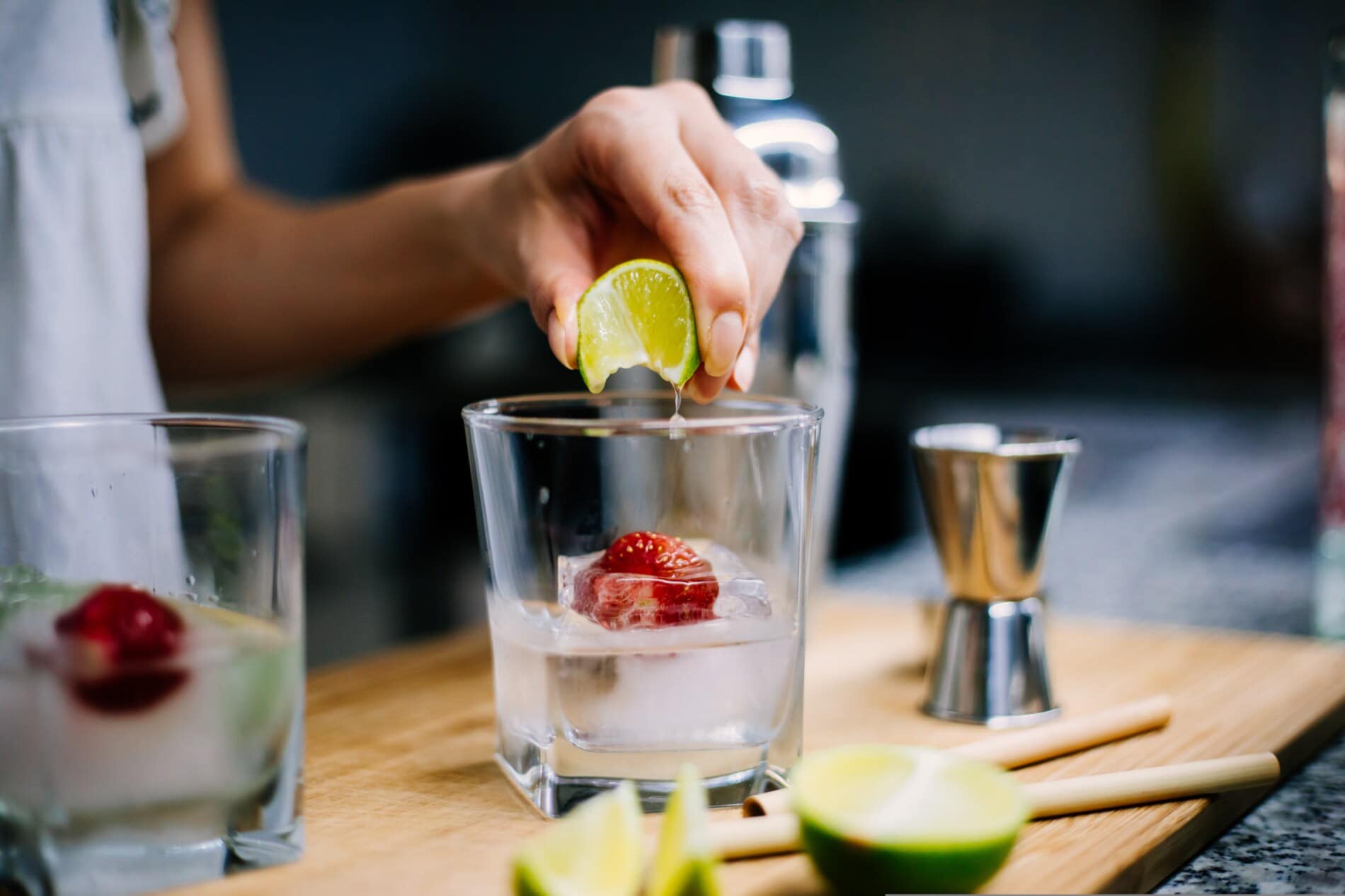Gin-Getränk mit einer Erdbeere im Eiswürfel und Limette Gin-Getränk mit einer Erdbeere im Eiswürfel und Limette