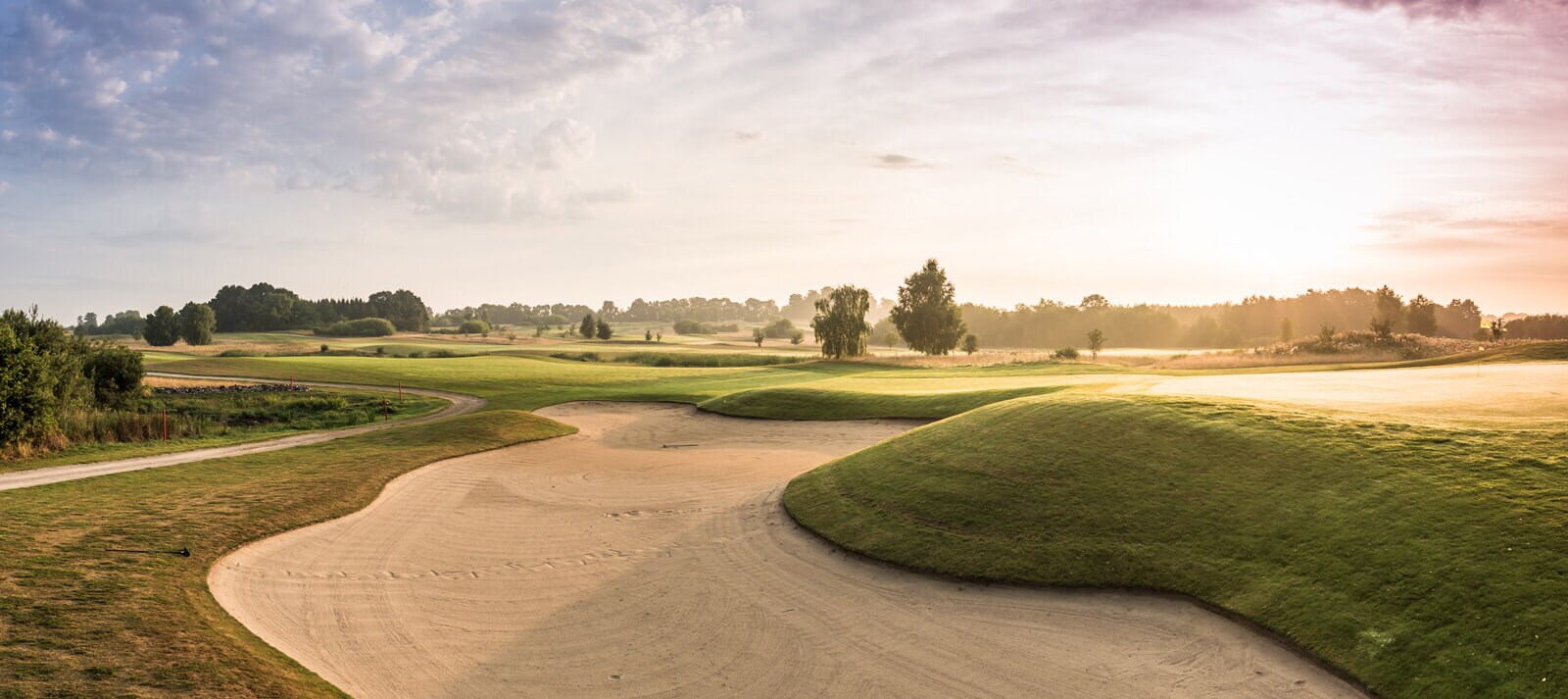 Blick auf eine Golfbahn vom Sand aus