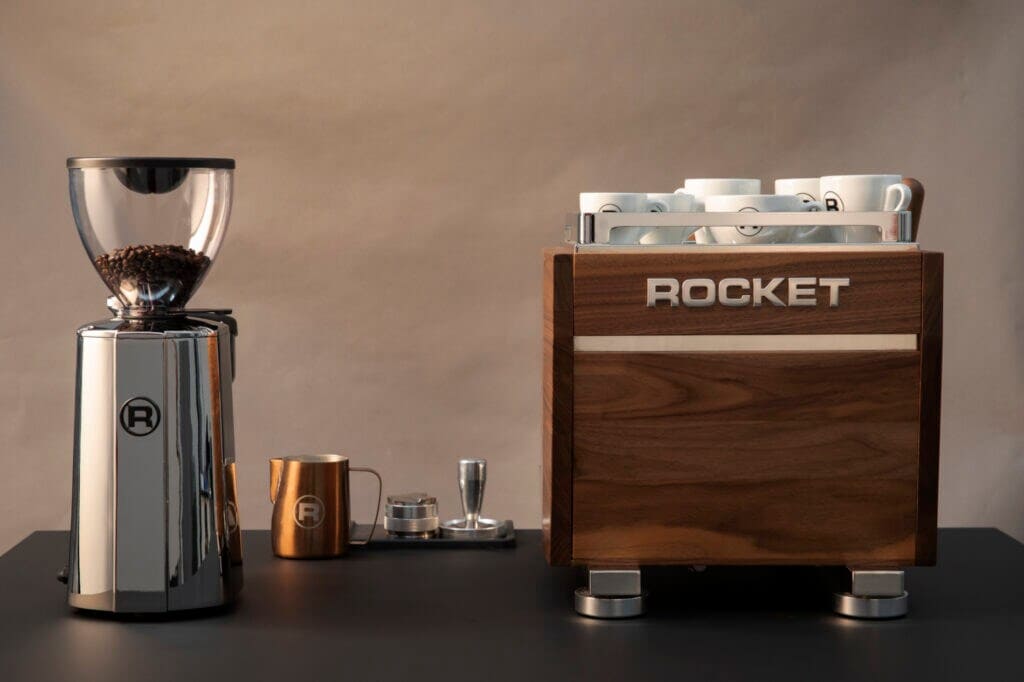 Edle Espressomaschine, Kaffeemühle und Milchkännchen auf einem Tisch Edle Espressomaschine, Kaffeemühle und Milchkännchen auf einem Tisch