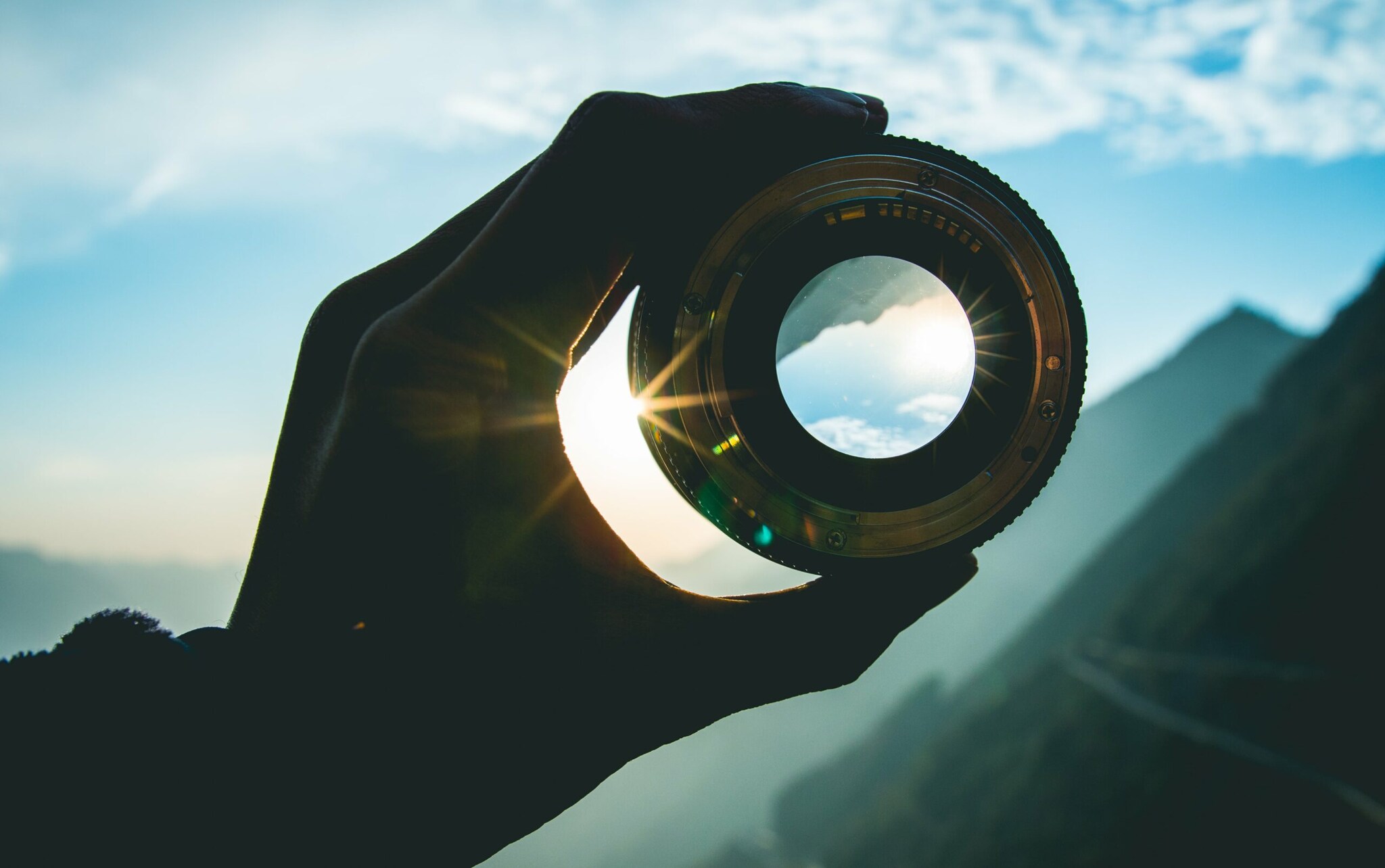 Eine Hand hält ein Objektiv gegen die Sonne Eine Hand hält ein Objektiv gegen die Sonne