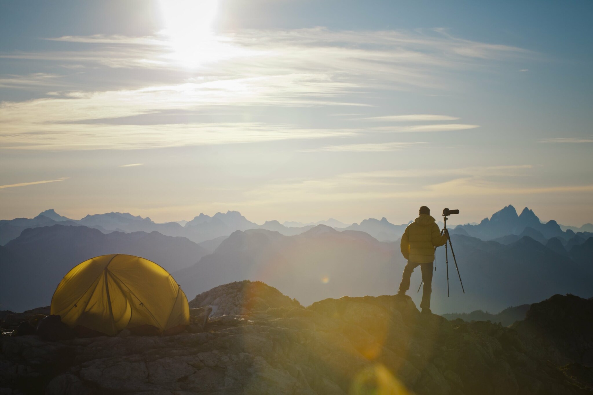 Ein Zelt und ein Mann mit Fotoapparat vor einer Hochgebirgskulisse