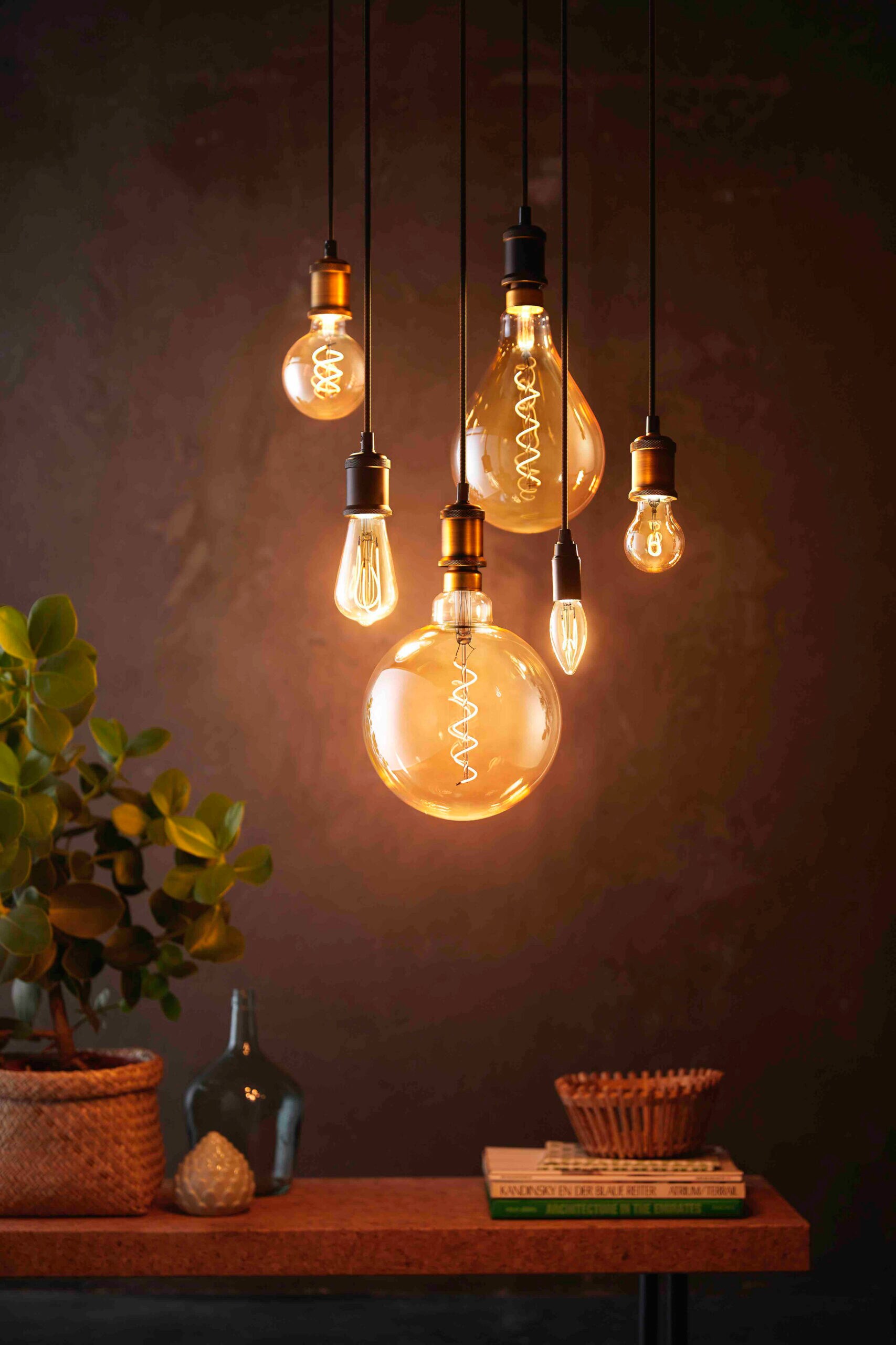 Mehrere dimmbare LED-Leuchten im Vintage-Look hängen gebündelt über einem Tisch. Mehrere dimmbare LED-Leuchten im Vintage-Look hängen gebündelt über einem Tisch.