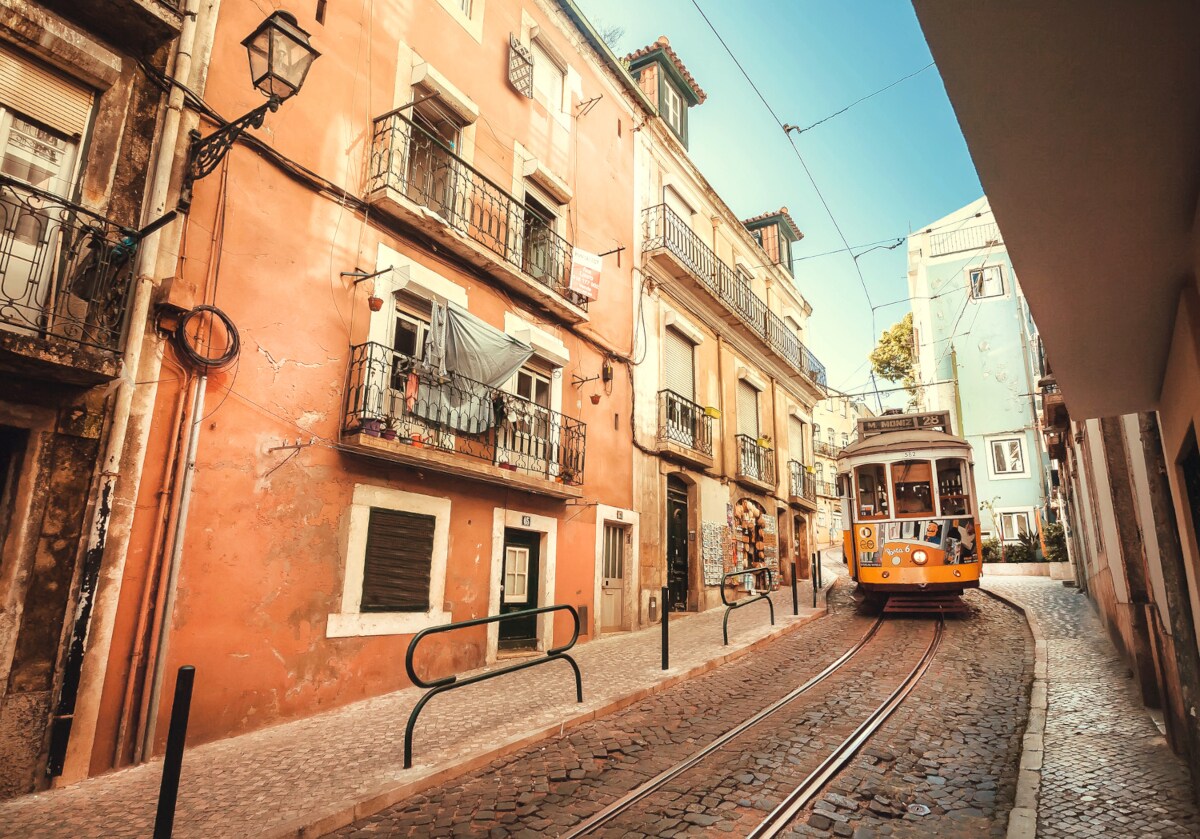 Eine Straßenbahn fährt durch eine ruhige Straße mit alten Häusern in Lissabon Eine Straßenbahn fährt durch eine ruhige Straße mit alten Häusern in Lissabon