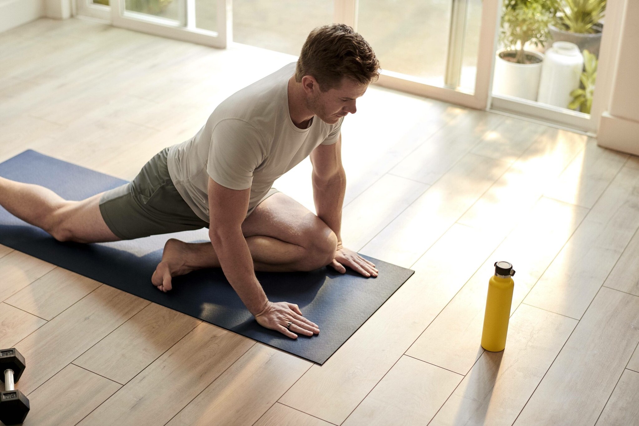 Ein Mann mit einem Oura-Ring am Finger trainiert Yoga