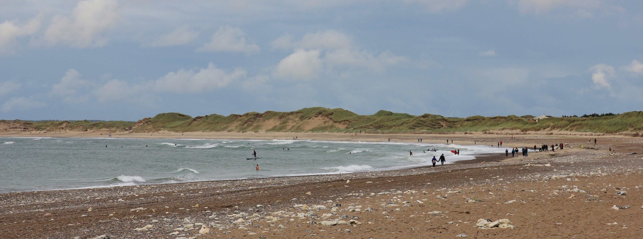 Ein Strand mit Spaziergängern und Surfern