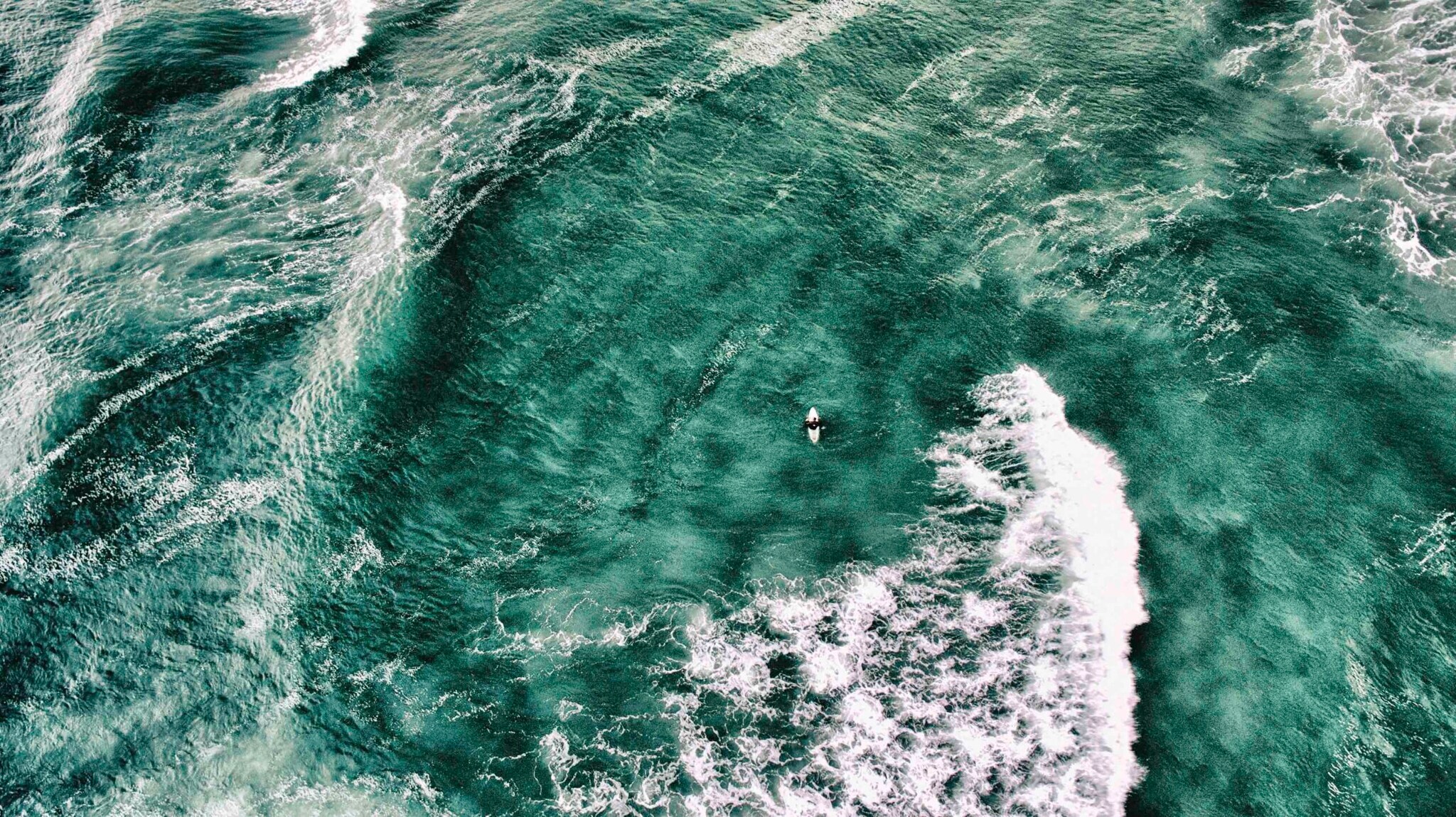 Wellenreiter:in auf einem Brett umgeben von Wasser