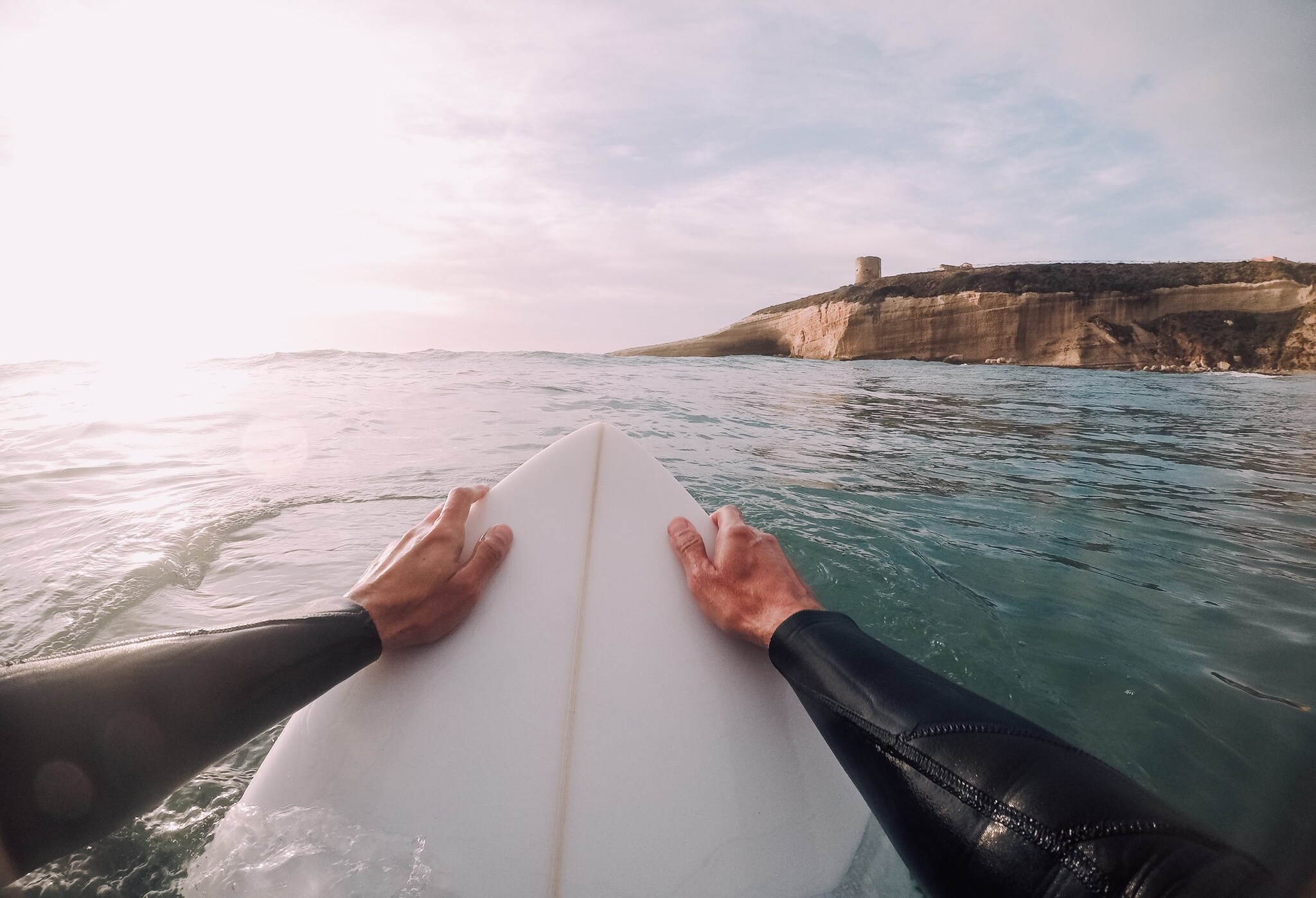 Mann auf einem Surfbrett steuert auf eine Küste zu