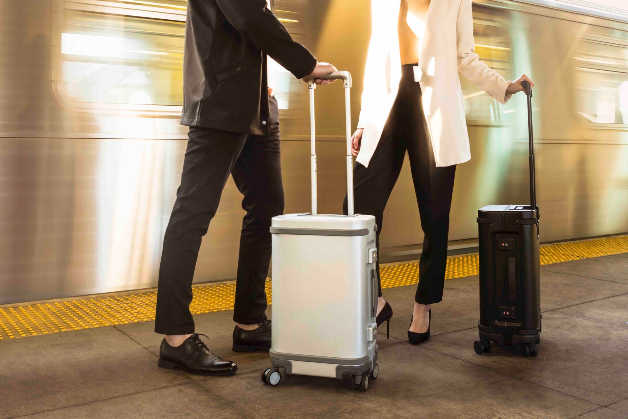 Zwei Menschen mit einem Koffertrolley in der Hand stehen am Gleis einer U-Bahn. Zwei Menschen mit einem Koffertrolley in der Hand stehen am Gleis einer U-Bahn.