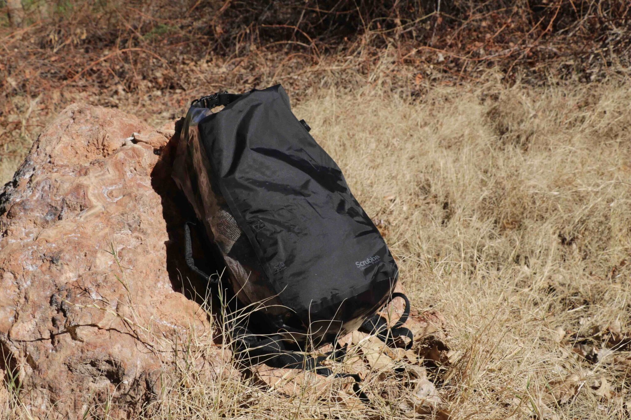 Schwarzer Outdoor-Rucksack an einem großen Stein gelehnt. Schwarzer Outdoor-Rucksack an einem großen Stein gelehnt.