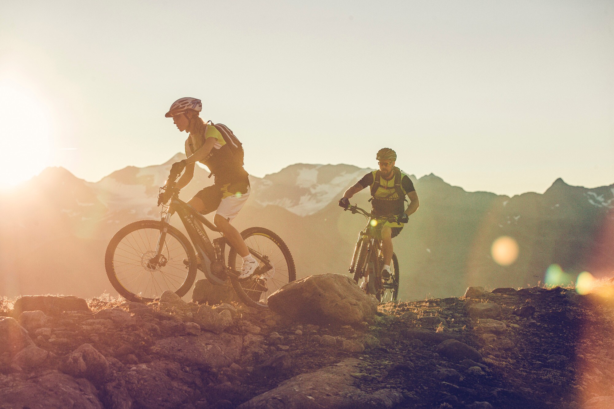 Zwei Personen mit E-Mountainbike auf einem Berggrat Zwei Personen mit E-Mountainbike auf einem Berggrat