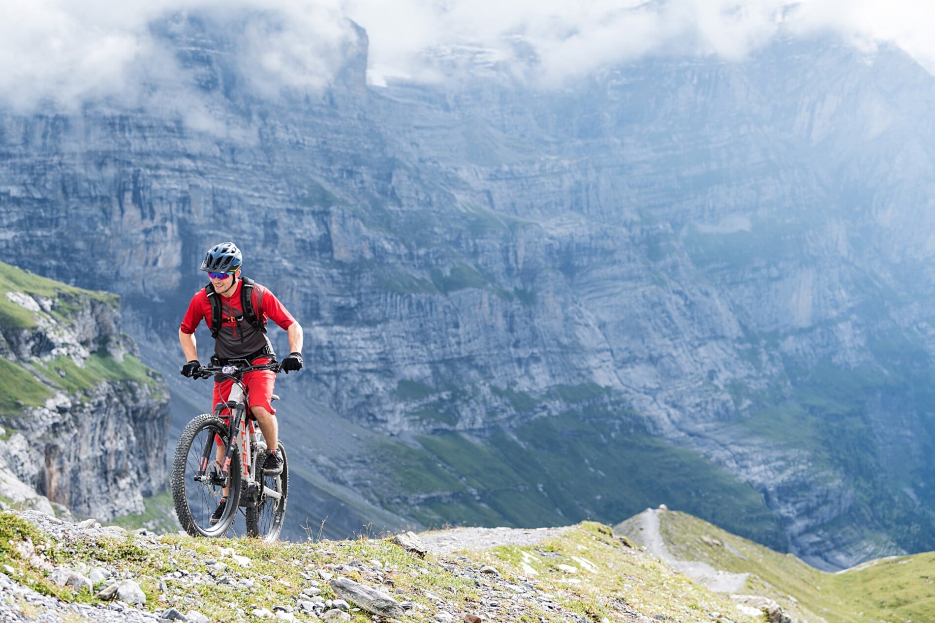 Ein Mountainbiker in rotem Dress vor einer mächtigen Felswand Ein Mountainbiker in rotem Dress vor einer mächtigen Felswand