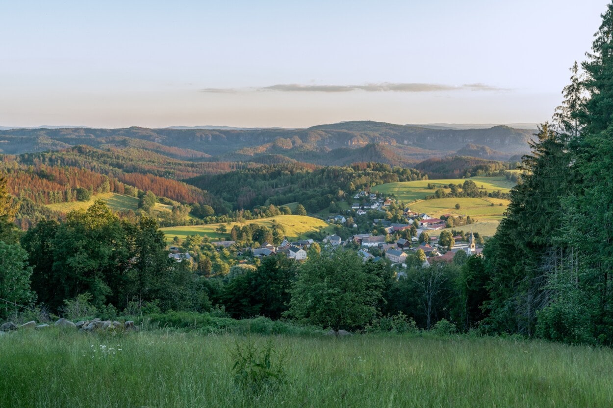 Blick auf einen idyllisch in bewaldeten Hügeln gelegenen Ort Blick auf einen idyllisch in bewaldeten Hügeln gelegenen Ort