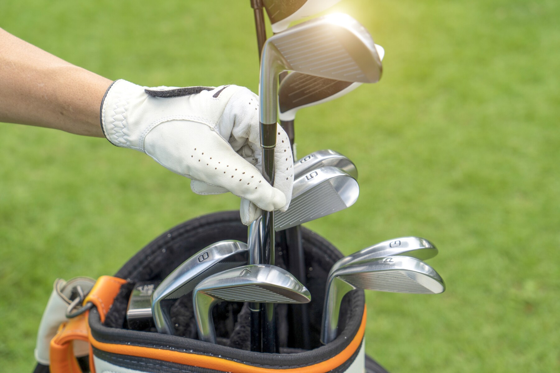 Eine Hand zieht einen Golfschläger aus einer Tasche Eine Hand zieht einen Golfschläger aus einer Tasche