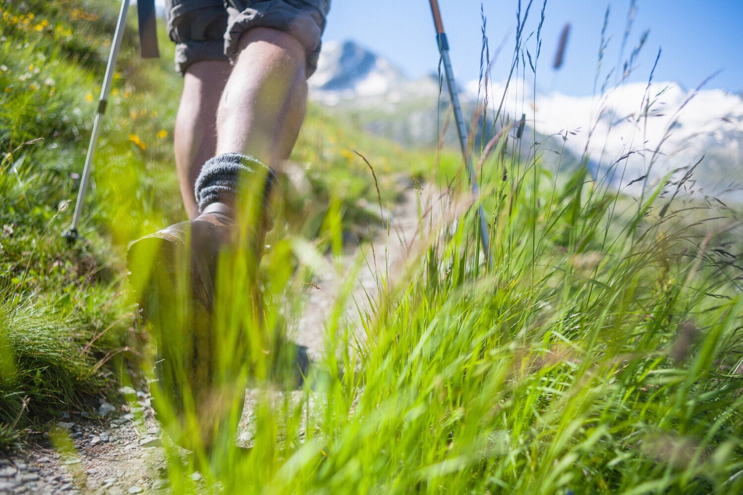 Die Beine eines Wandernden auf einem Pfad in alpinem Gelände