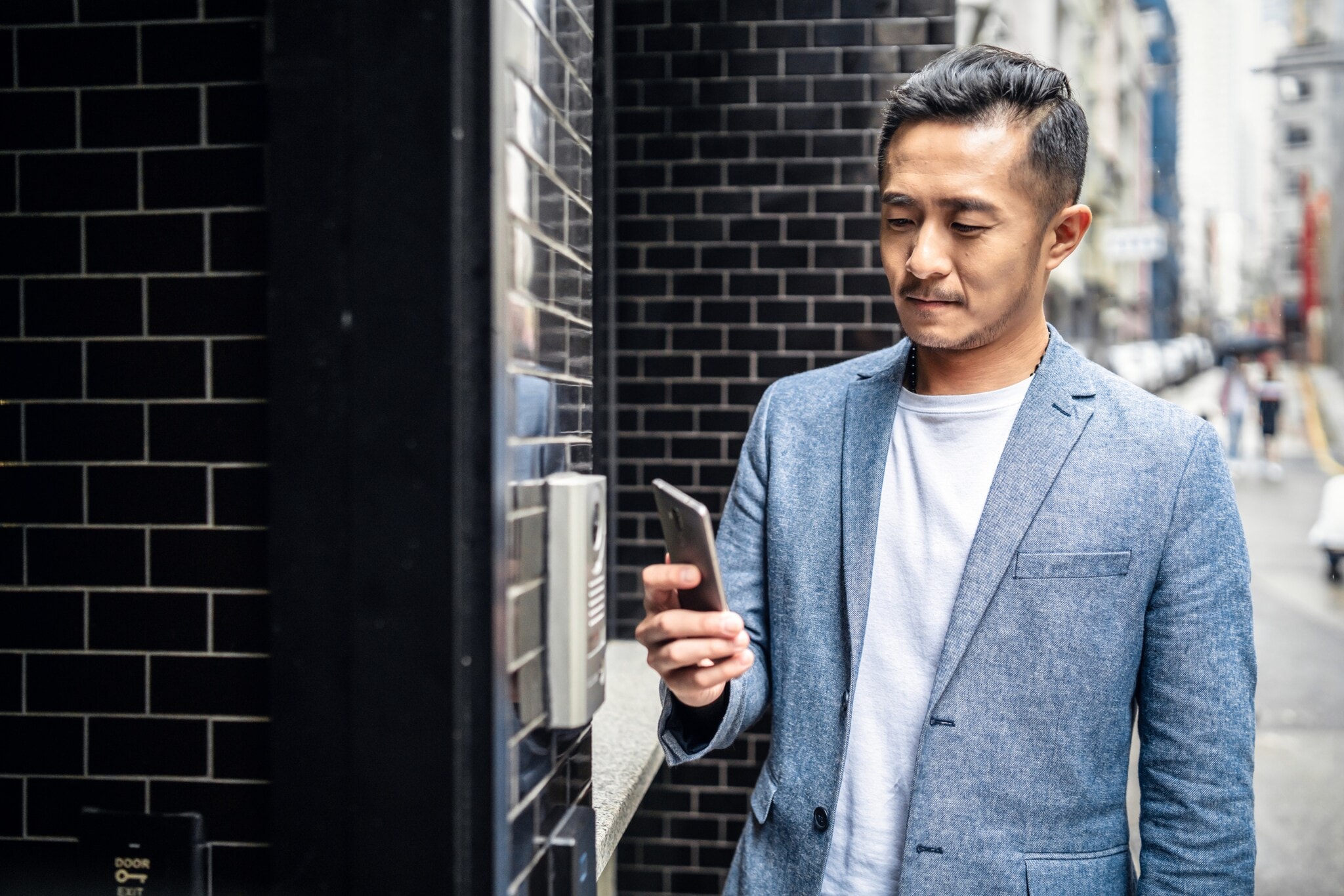 Ein Mann öffnet mit seinem Smartphone die Eingangstür Ein Mann öffnet mit seinem Smartphone die Eingangstür