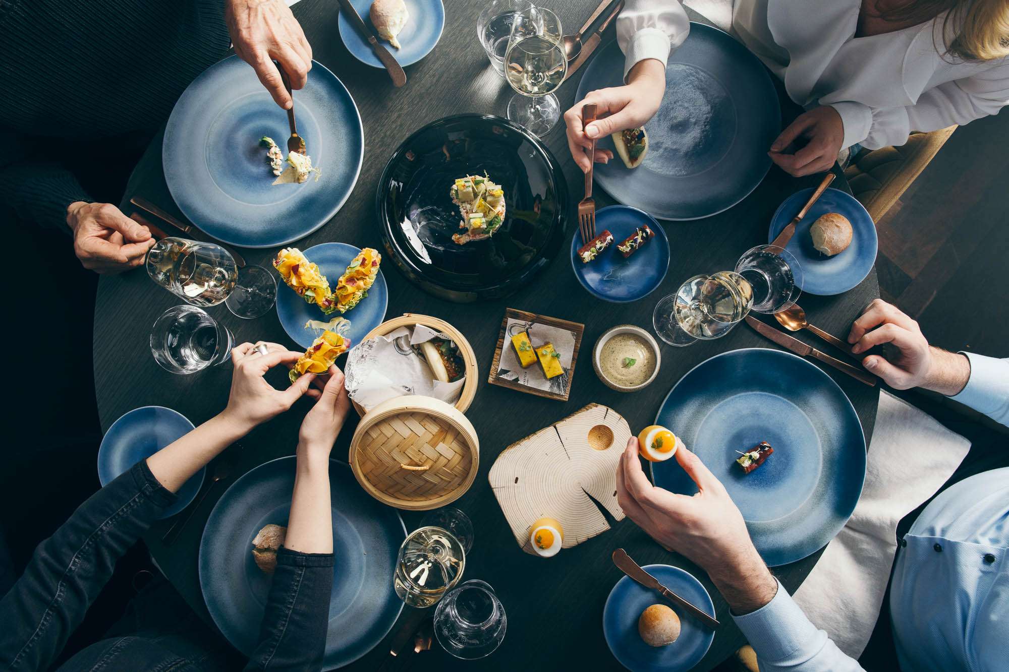 Vier Menschen sitzen an einem Tisch und teilen sich das Essen, Aufnahme aus der Vogelperspektive