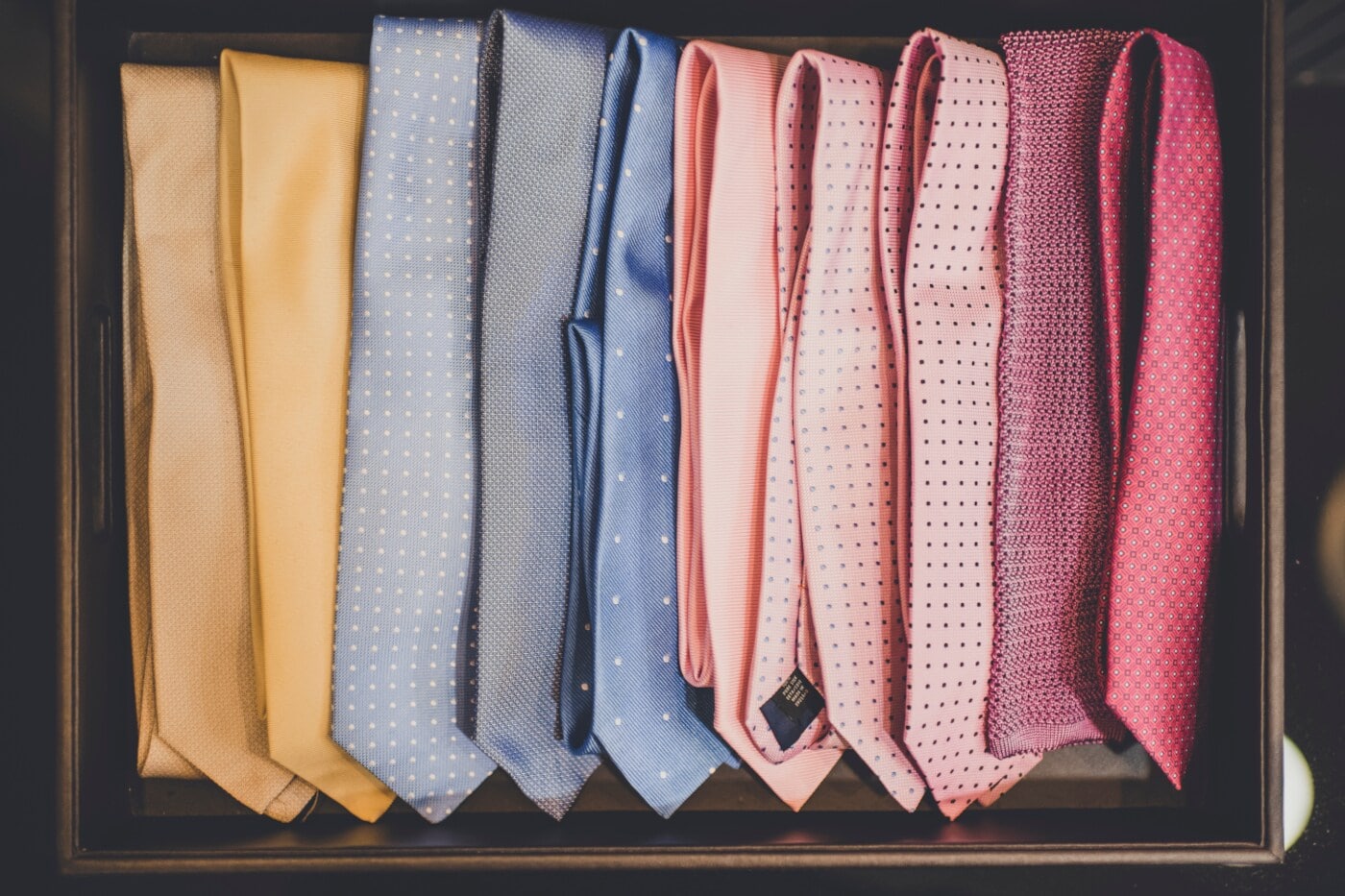 Krawatten in unterschiedlichen Farben liegen nebeneinander in einer Schachtel