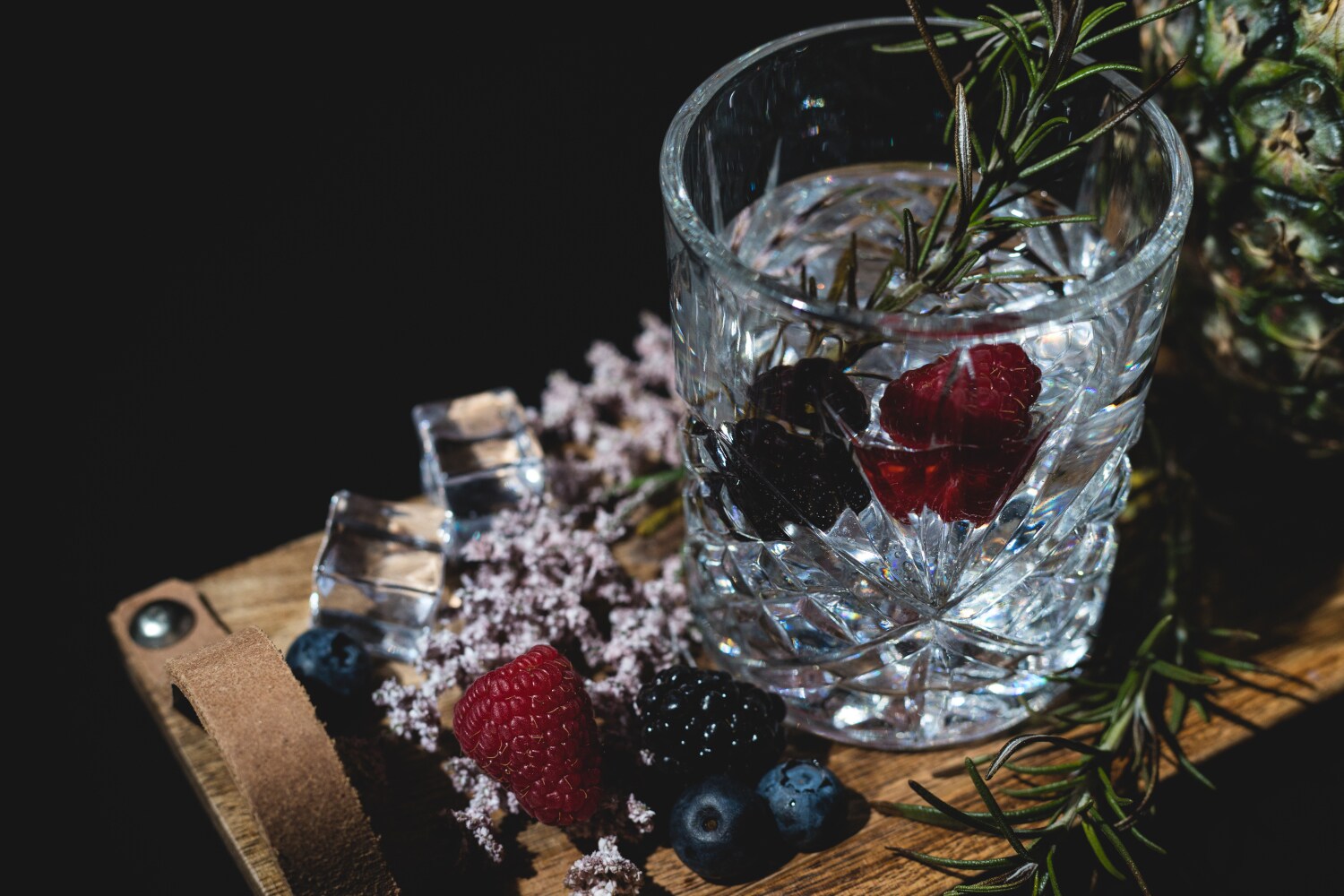 Ein geschliffenes Glas mit Gin, Beeren und Rosmarin