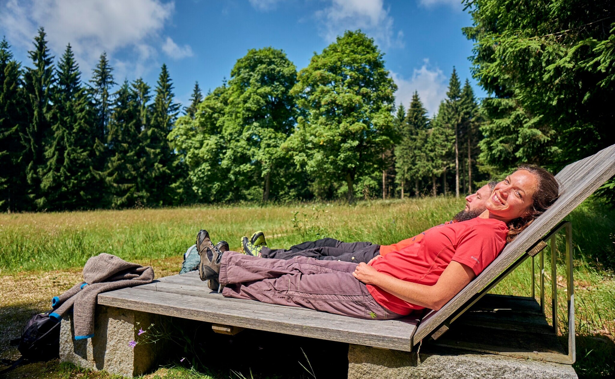 Ein Mann und eine Frau liegen auf Holzliegen und entspannen sich
